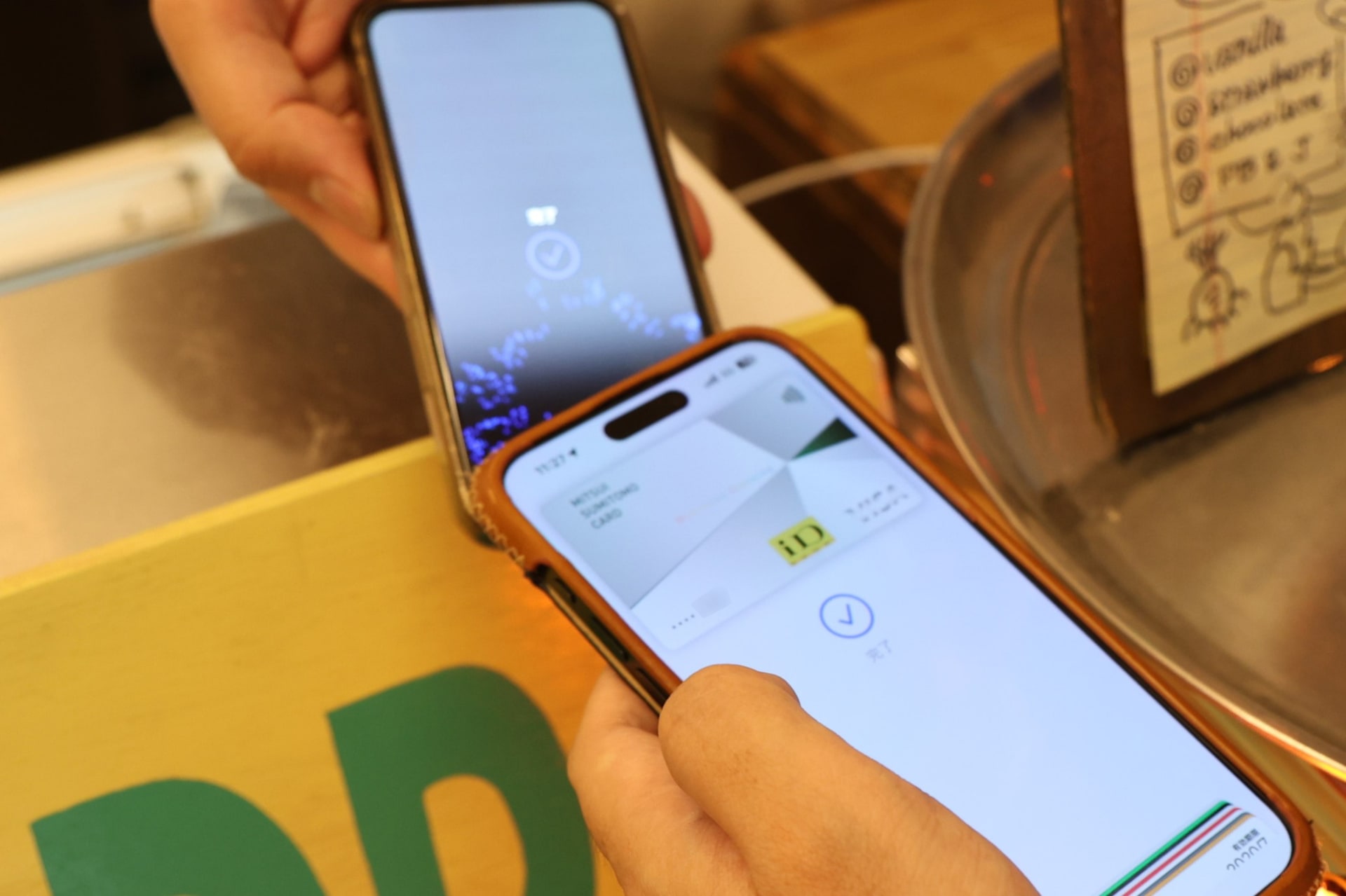 iPhoneのApple Payで決済しているところ。iPhoneのNFCリーダーは本体上部にあるので、付き合わせて決済するかたちになる