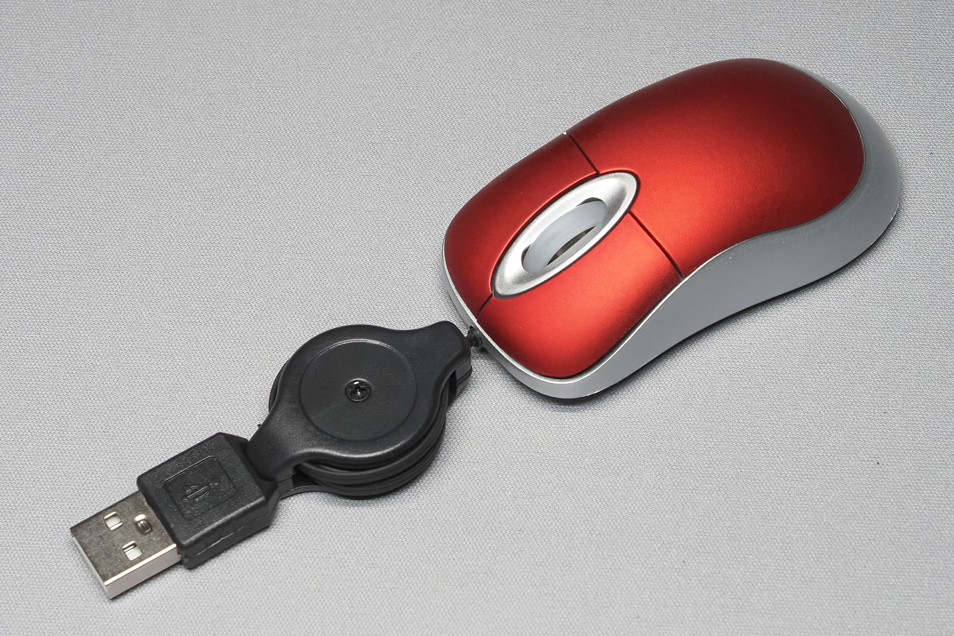 こんなマウス。大きさは75×40×20mm。巻き取りリールやUSB-A端子と本体のサイズ比がヘン！　目の錯覚的な……。