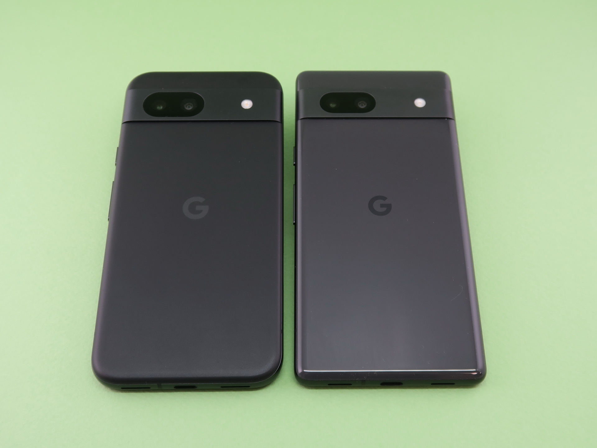 「Pixel 8a」（左）と「Pixel 7a」（右）の背面。ボディ形状の違いがよくわかる。カメラバーに内蔵された広角カメラ超広角カメラもデザインが変更された