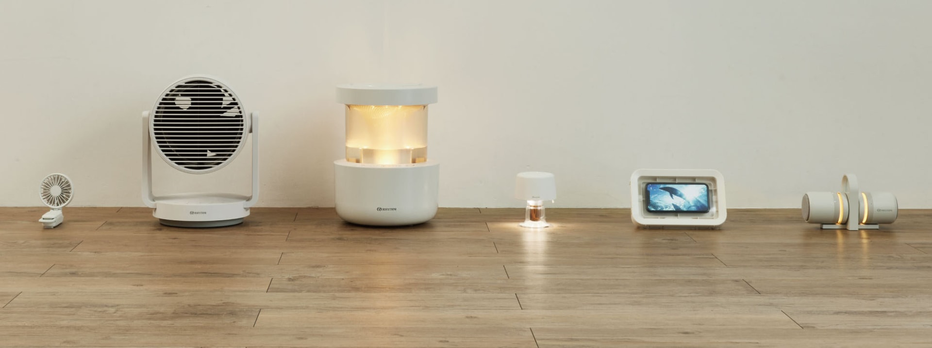 近年のリズム製品。左から、ポータブル扇風機<a href="https://rhythm.jp/lp/silkywindmobile3_1" class="strong bn" target="_blank">「Silky Wind Mobile 3.1」</a>、サーキュレーター<a href="https://rhythm.jp/lp/silkywindcirculator" class="strong bn" target="_blank">「Silky Wind Circulator」</a>、加湿器<a href="https://rhythm.jp/lp/mist300" class="strong bn" target="_blank">「MIST 300」</a>、アロマディフューザー<a href="https://rhythm.jp/lp/aromafunhour" class="strong bn" target="_blank">「AROMAFUN hour」</a>、防水スマートフォンケース<a href="https://rhythm.jp/lp/magcase" class="strong bn" target="_blank">「MAGCASE S」</a>、<a href="https://rhythm.jp/lp/magspeakerduo" class="strong bn" target="_blank">「MAGSPEAKER DUO」</a>。