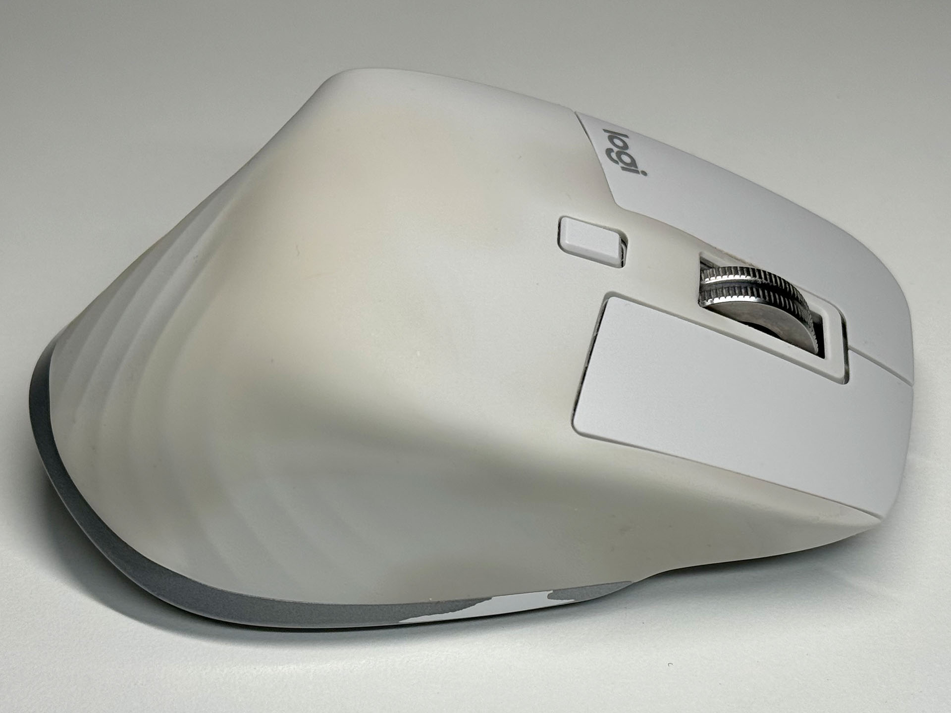 ブリーディングが収まりつつあるMX MASTER 3S。薄茶色に変色している部分はブリーディングによる変色だと思われる。ブリーディングが起きていない場所はクリックボタンと同色のまま。ともあれ、ブリーディングが収まりつつある現在、フキフキするほどにモトの色に戻っているように思う。小指が当たるあたりの下部エッジは、フキフキしたことにより硬質樹脂素材表面の塗装が剥げた跡と思われる。