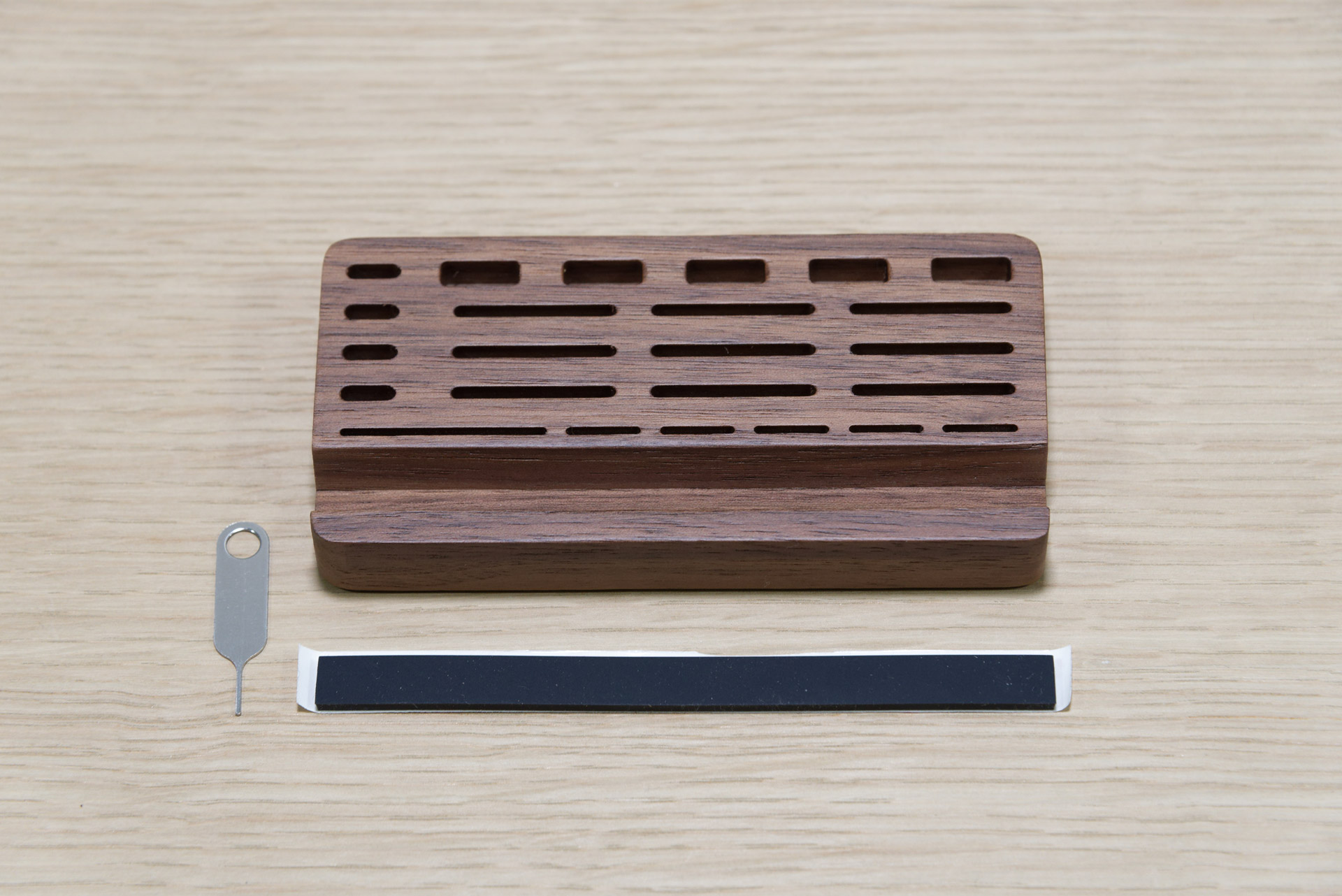 100％木製のメモリスタンド。手前の黒い帯状のものは付属品で、スマホを立てる溝に敷くクッションと思われる