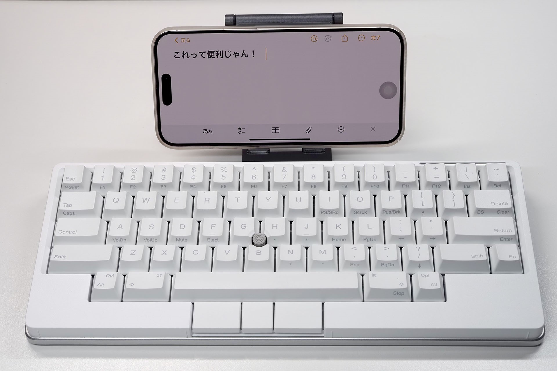 モバイルデバイスとキーボードのサイズがちぐはぐだが、「HHKB Studio 雪」はタイプしやすいうえにマウス機能もあるので、iPhoneなど小型デバイスでテキストを書くのがとても快適である。ちなみに、写真の端末はiPhone 15 Pro Maxだが、「HHKB Studio 雪」とはBluetooth接続でもUSB-C接続でもとくに問題なく使えた。iOS側で設定すればマウスポインターも出てくるョ！