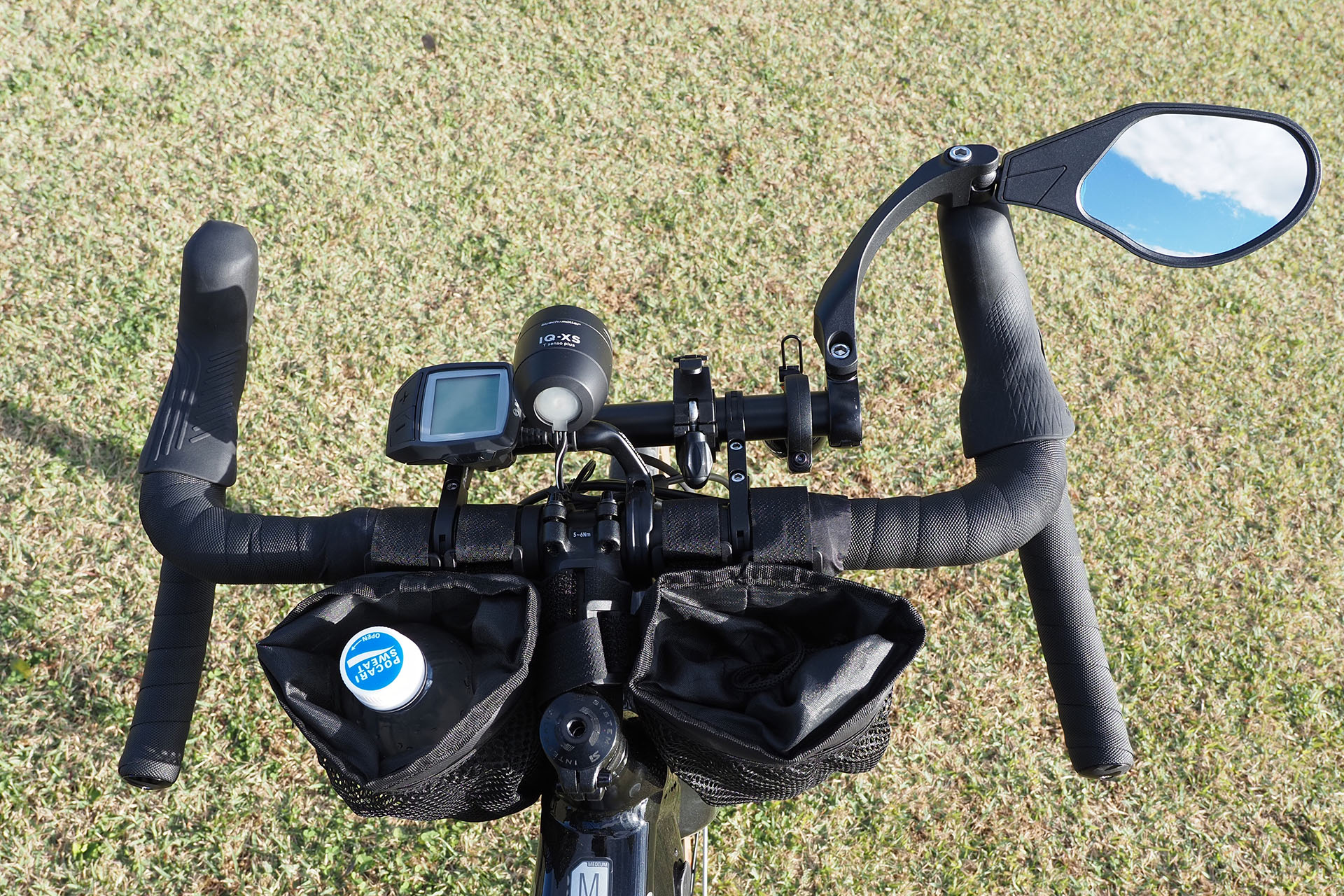 ハンドルには大きなミラーも。道路上での事故の危険は後ろからもやってきたりするからだ。ハンドル手前には2つのドリンクホルダー（ファブリック製）を装着。左に飲料、右にiPhoneを入れている。猫を発見したら速攻でiPhoneを取り出して撮影するためだ。あと今どきの複雑な機構を備えたスマートフォンは、ハンドルなどにダイレクトに装着するとカメラなどが故障する可能性が高まる