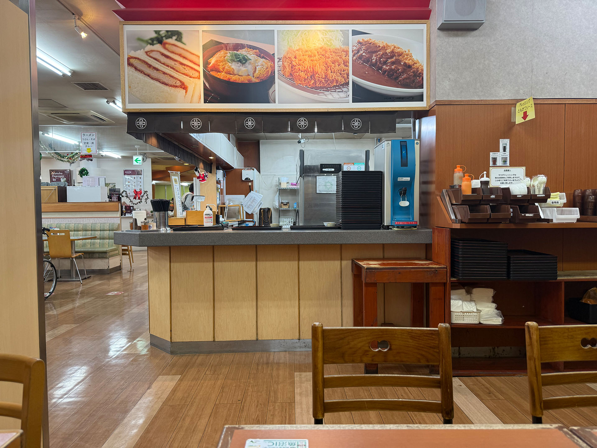 パーキングエリアで食事に寄った飲食店内。手前の椅子とテーブルが邪魔かニャ？　と思ったら、そこを範囲選択して生成塗りつぶし機能を使えばいい。