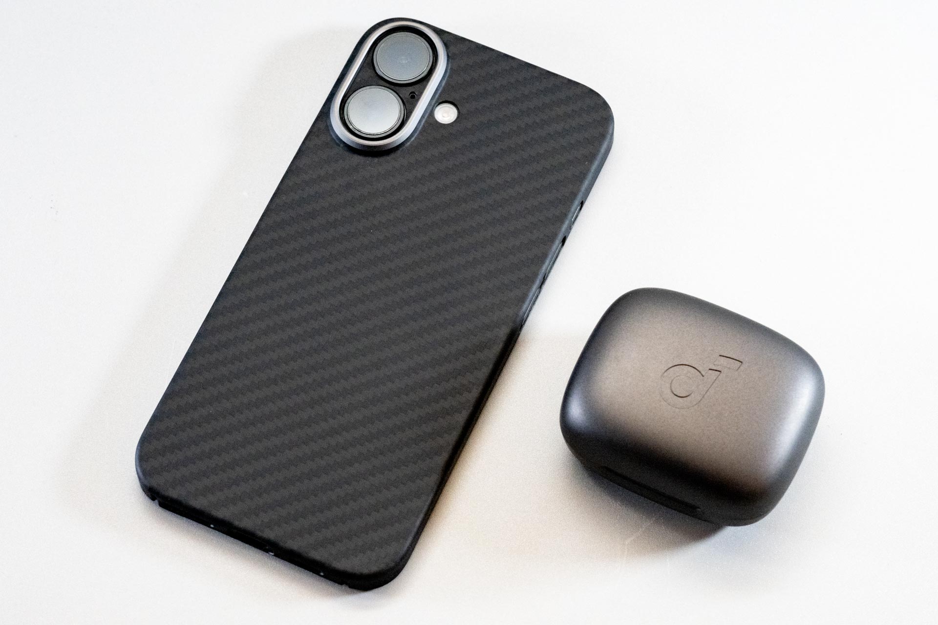 スマートフォンと並べてみると小ささがよくわかります。ヘッドバンド型の骨伝導型やイヤーフック型よりもコンパクトで持ち運びも便利そうです