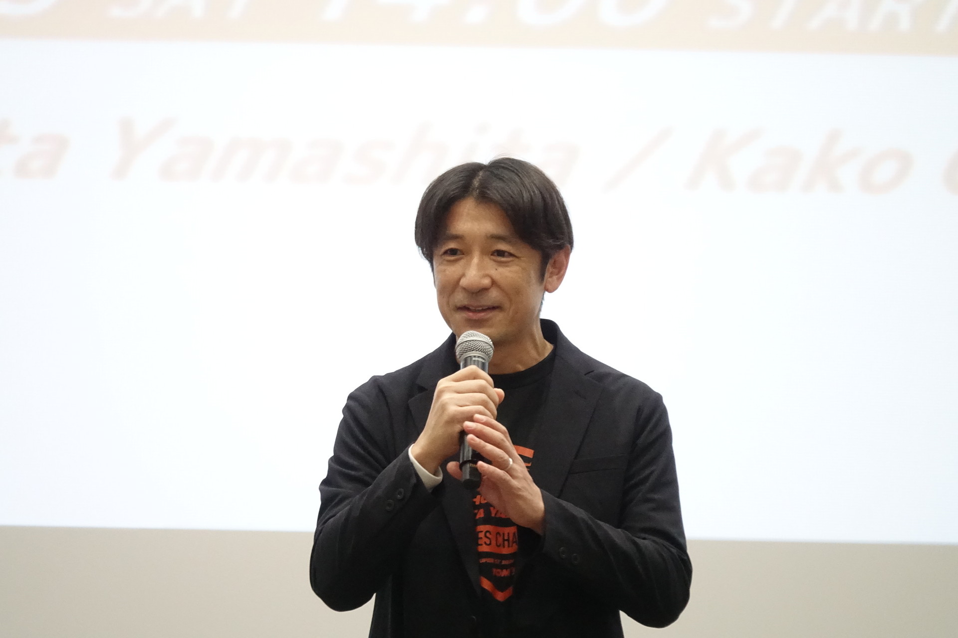 KDDI ブランドマネジメント部長の坂本伸一氏（左）もあいさつ。TOM'Sの神山裕示氏（右）もトークに参加した