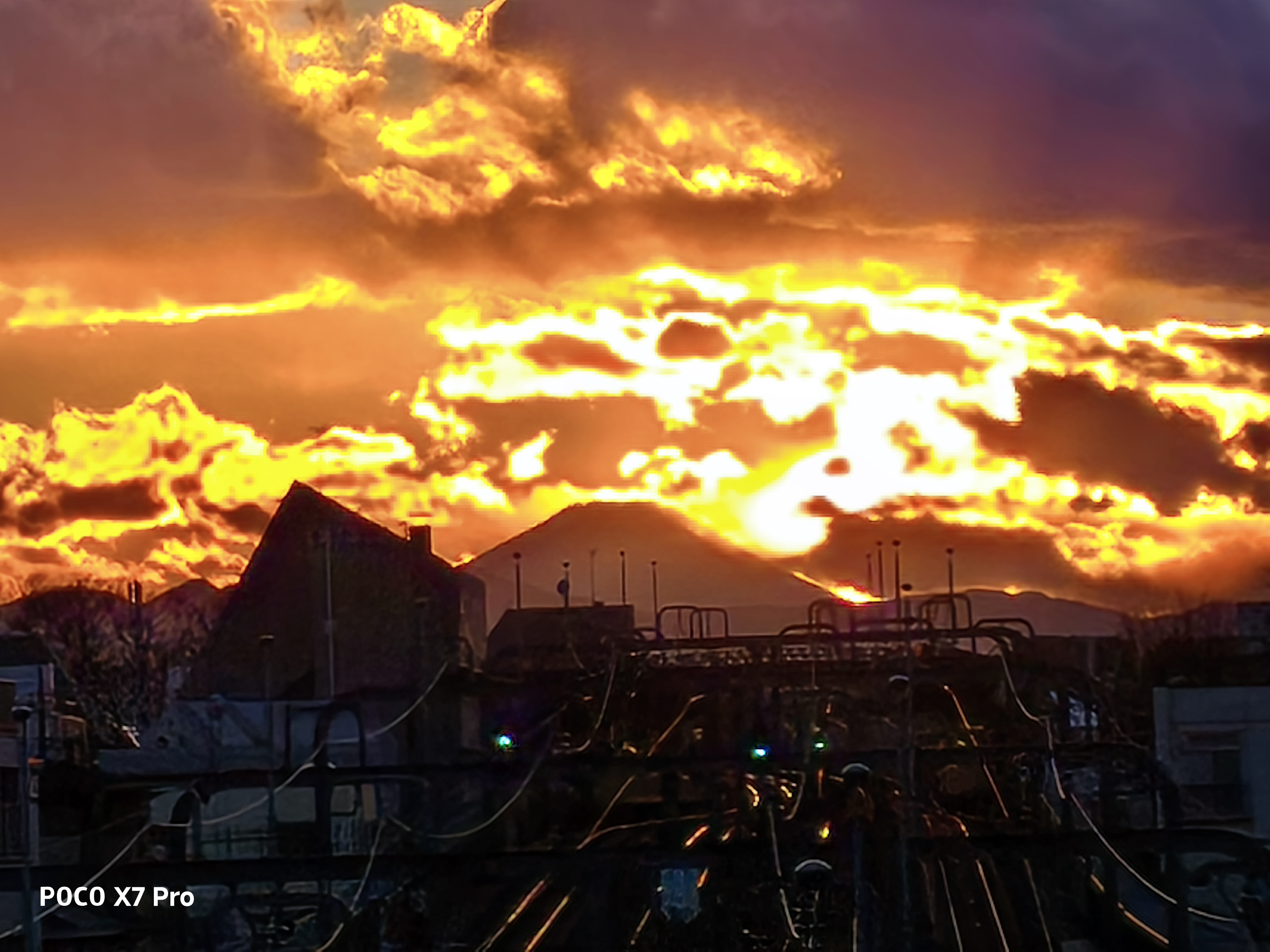 日没の夕景を撮影。夕日の色合いはきれいだが、光が強いため、手前側の線路などはややつぶれてしまっている