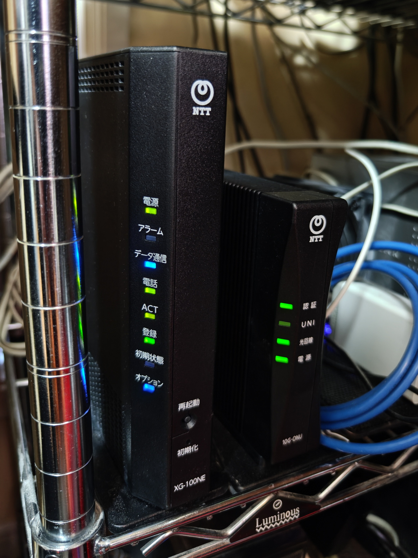 無事に設置できた「ドコモ光 10ギガ」のホームゲートウェイ「XG-100NE 光電話ルーター」（左）と「ドコモ光 10ギガ」対応のONU「10G-EPON」（右）。「SCM-PDS型「MK」E 光加入者線終端装置」は柵の奧に設置してしまったので、今後、この2台の隣に置いて、並べて設置する予定。