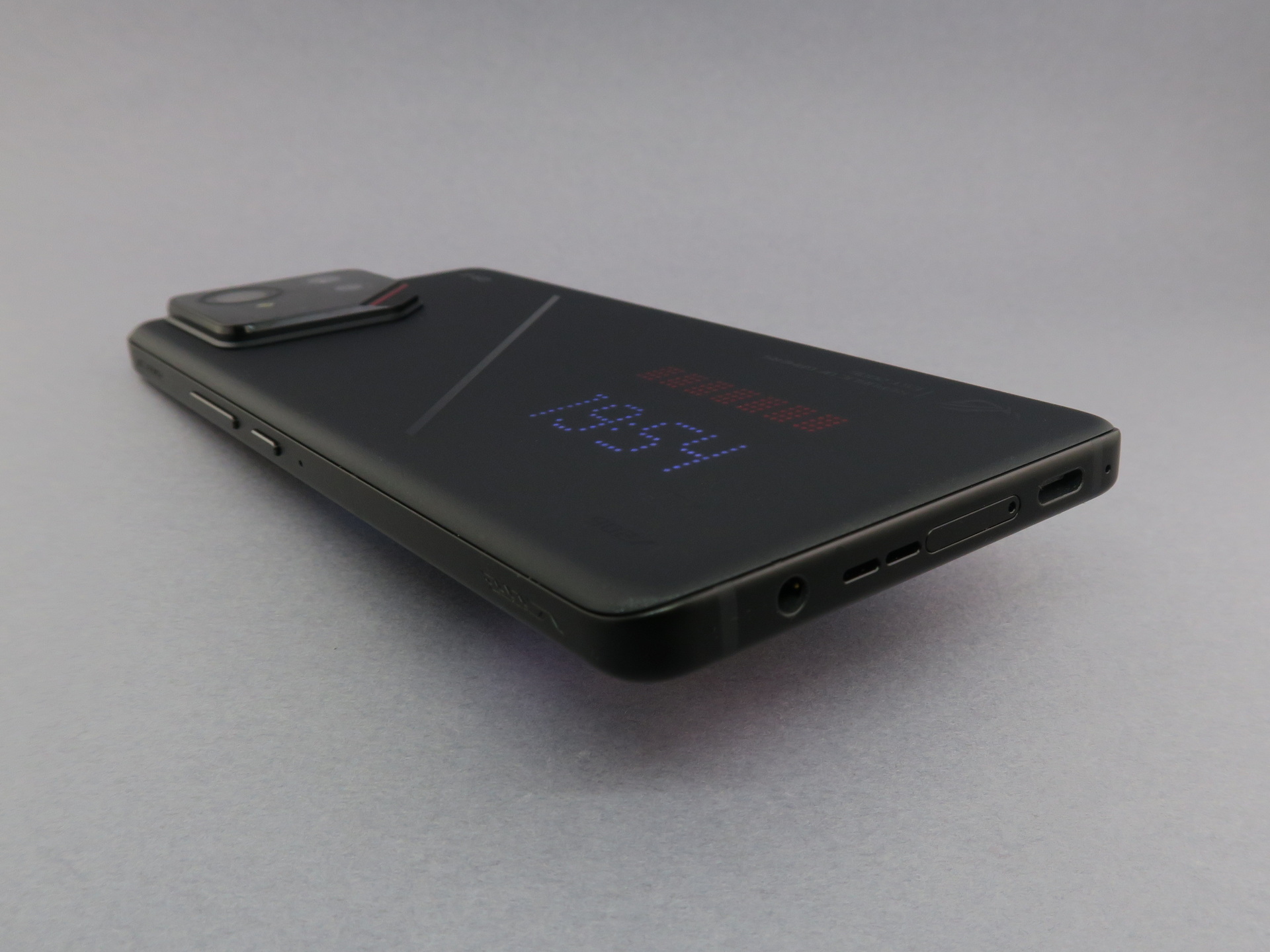 「ROG Phone 9 Pro」の下部は中央にピンで取り出すタイプのSIMカードスロット、右側面寄りの位置（写真左側）に3.5mm径のマイクロホン／ヘッドホン・コンボジャック、左側面寄りの位置（写真右側）にUSB Type-C外部接続端子を備える