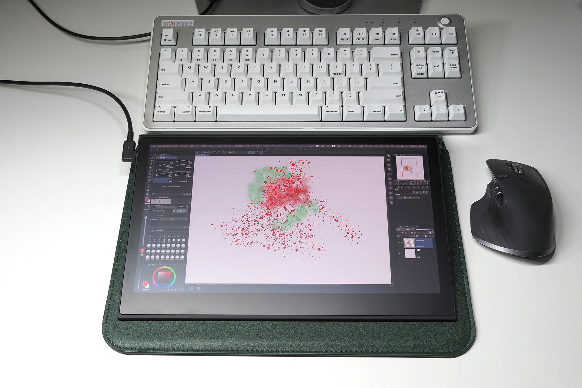 A4の紙くらいのサイズ感なので、机上でもあまり邪魔にならない。Wacom Movink 13の下にある緑色のものは、ノートPC／タブレット用のやや硬めのソフトケースで、フタの部分を立てると傾斜をもってWacom Movink 13を置ける。Wacom Movink 13は意外なほどの剛性感があるので、その状態で使ってもとくに問題ナシ。