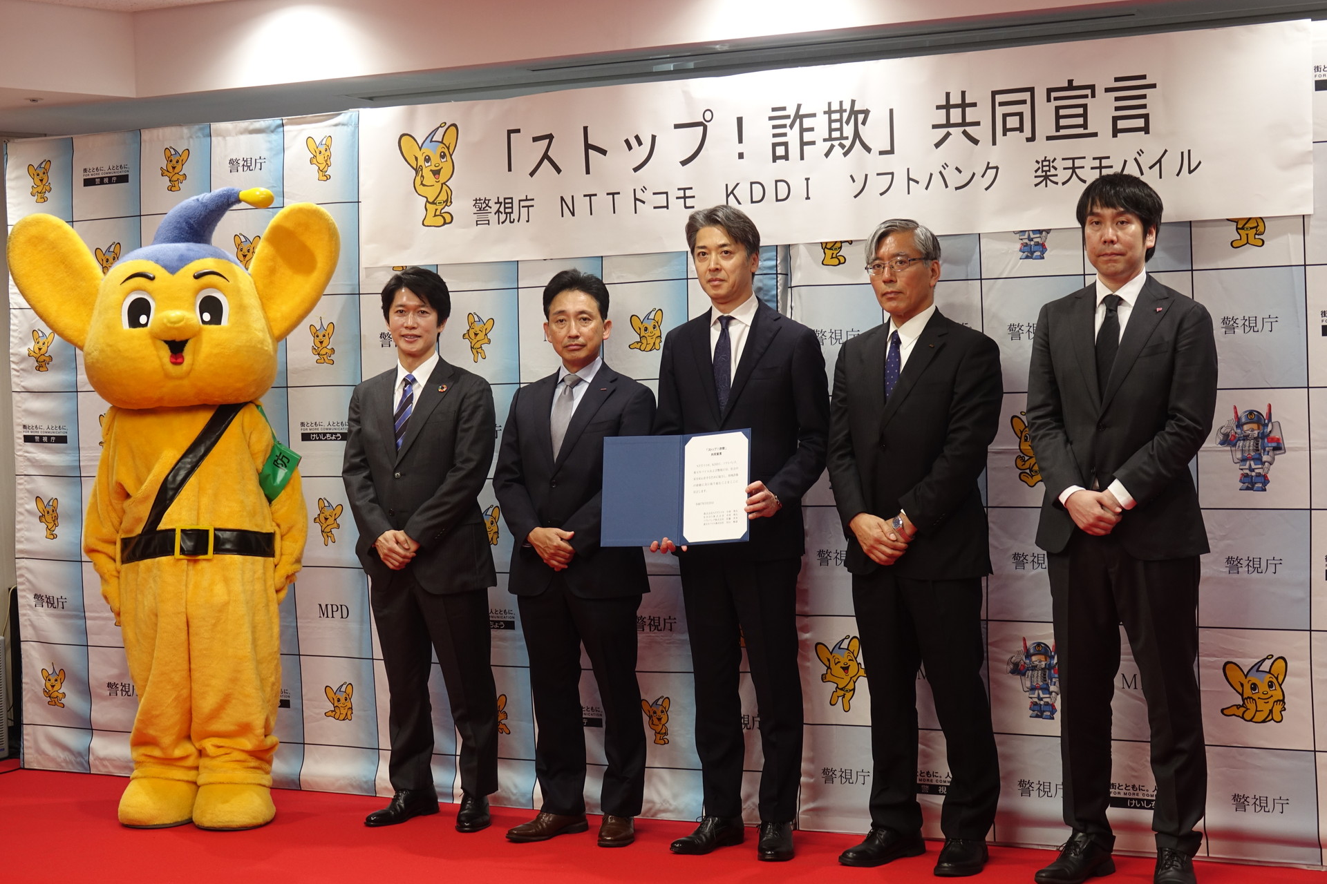 左からピーポくん、ソフトバンク 佐藤英幸氏、ドコモ 小林啓太氏、鎌田徹郎 副総監、KDDI 中里靖夫氏、楽天モバイル 谷山順道氏