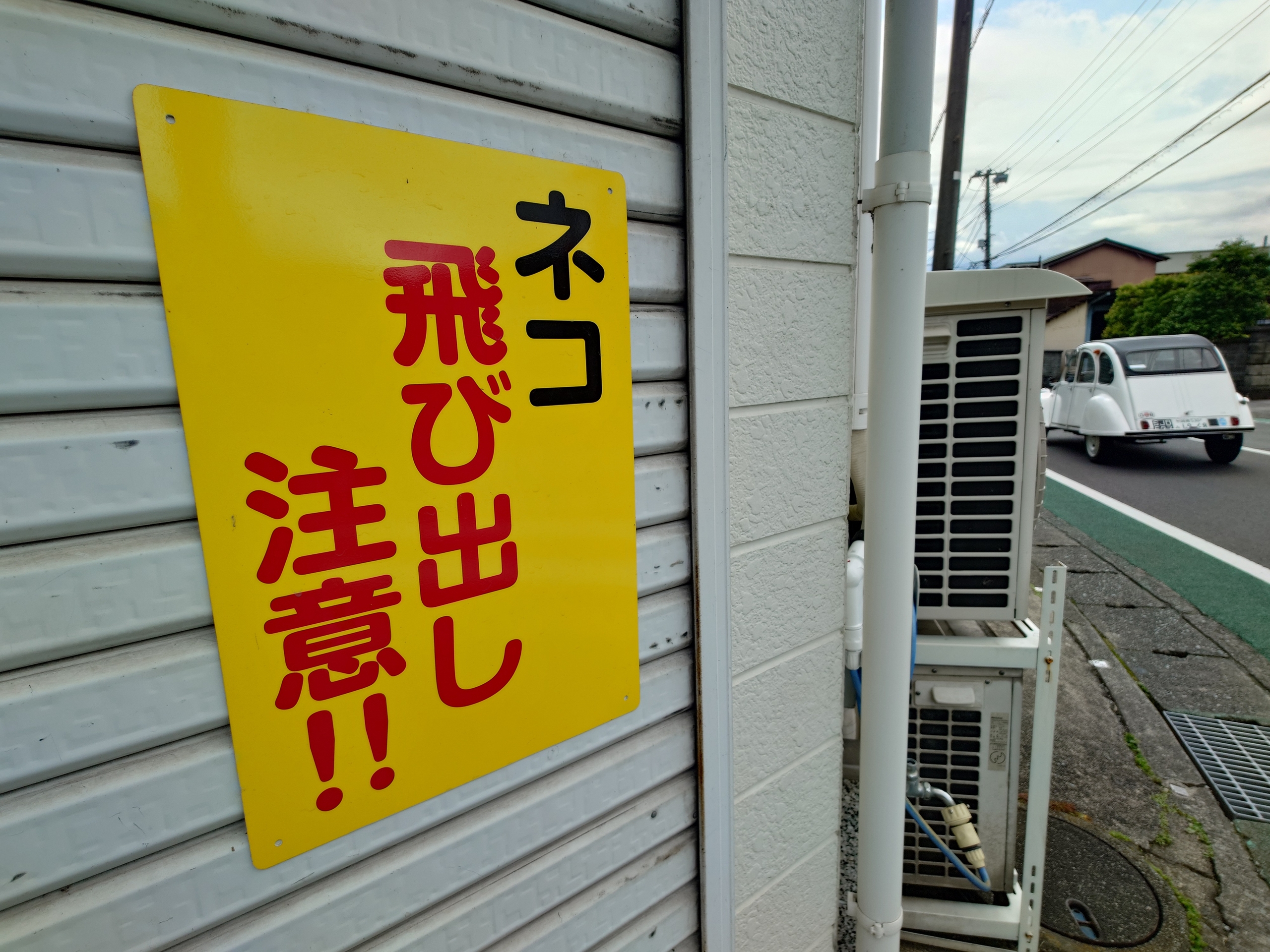 超広角カメラはスナップショット撮影に有効だ。広大な画角は「ネコ飛び出し注意！！」という看板と走り去るビンテージカーをしっかりとフレーム内に収めてくれた