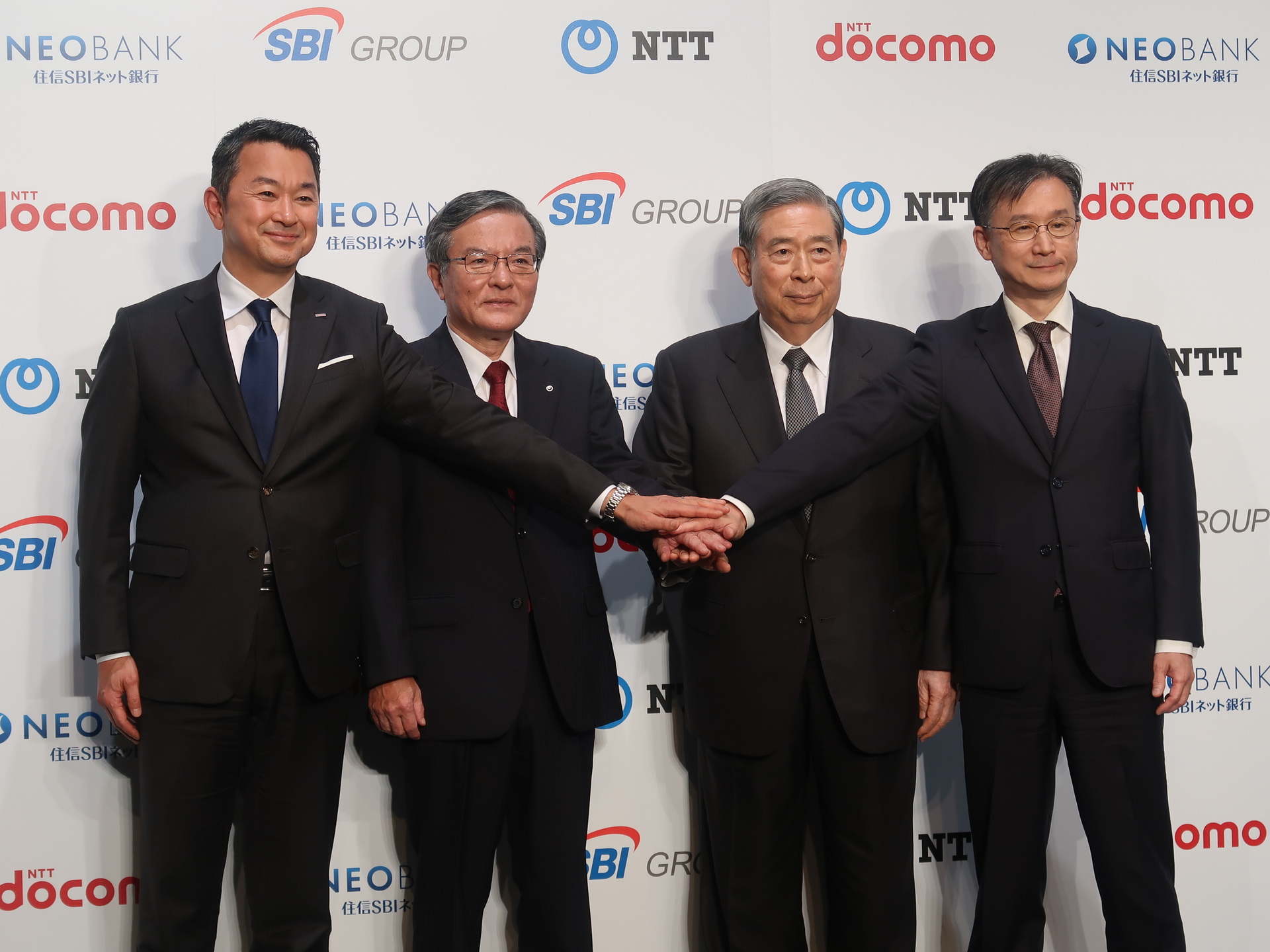 記者会見後のフォトセッションに収まる4社の首脳陣。左から順に、NTTドコモ 代表取締役社長CEOの前田義晃氏、NTT（持株）代表取締役社長の島田明氏、SBIホールディングス 代表取締役会長兼社長の北尾吉孝氏、住信SBIネット銀行 代表取締役社長の円山法昭氏