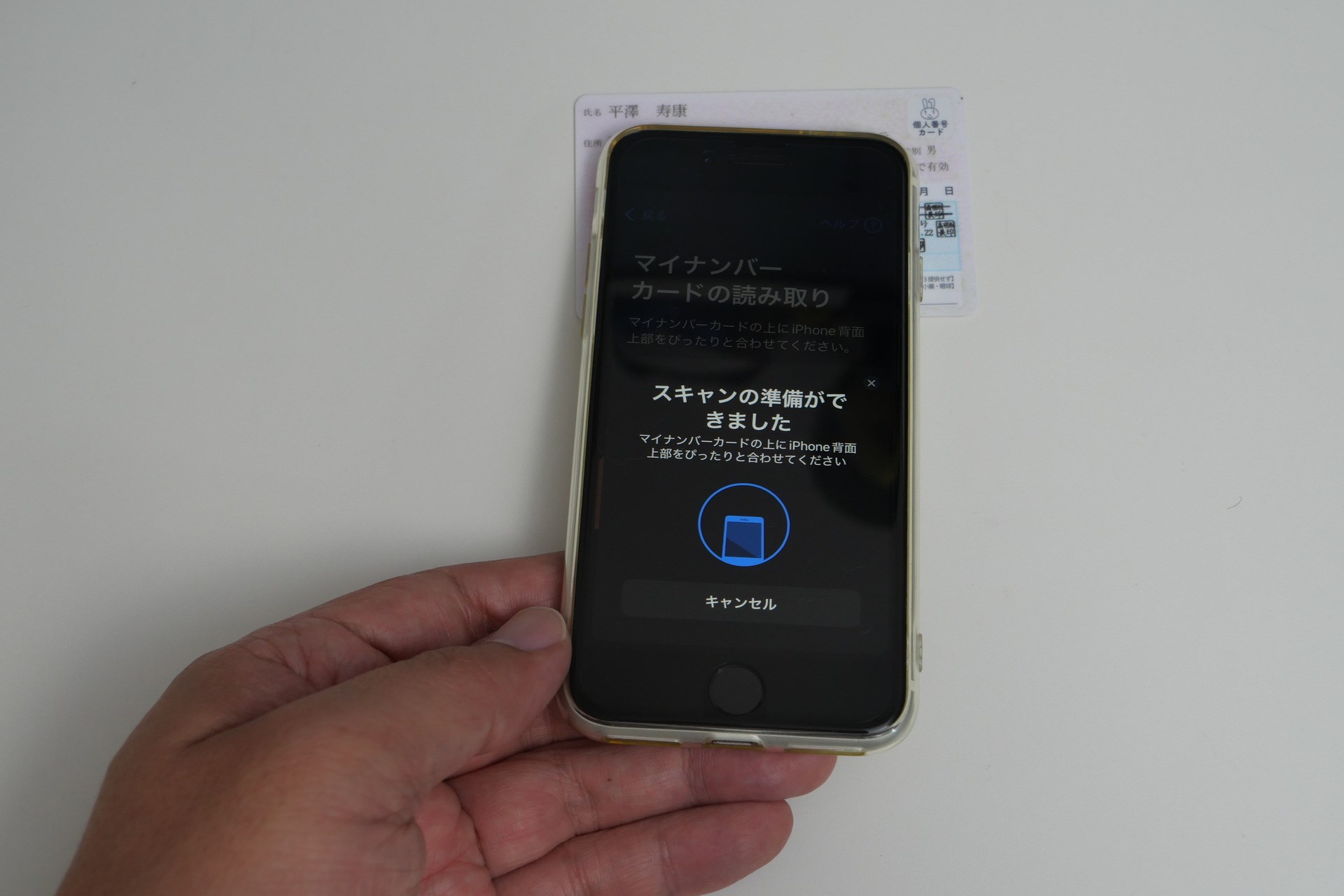 iPhoneの上部背面にマイナンバーカードを接触させて、動かさずしばらく待つ