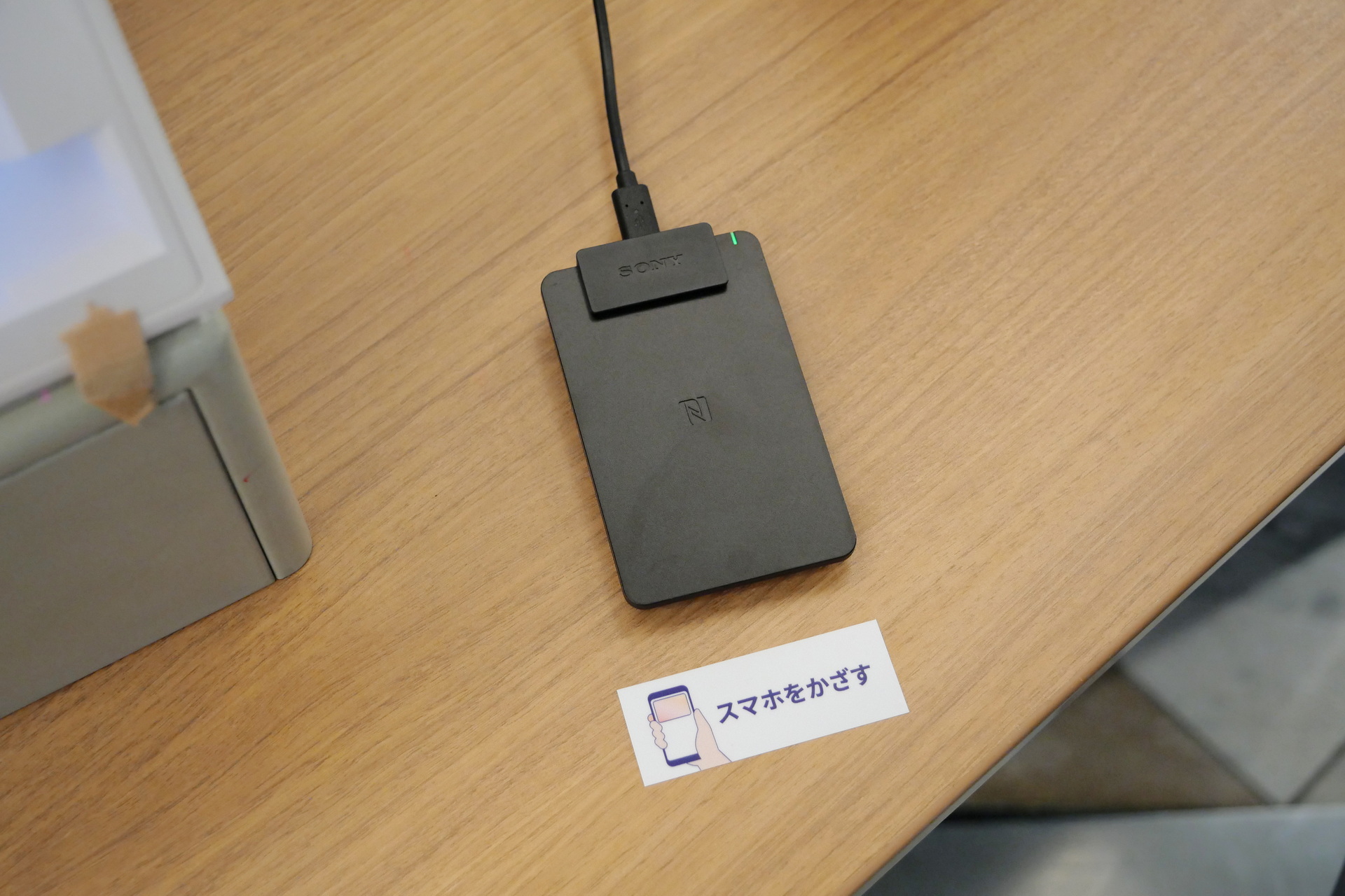 顔認証付きカードリーダーの横に、スマホ搭載のマイナンバーカード情報を読み取るためのカードリーダーを設置