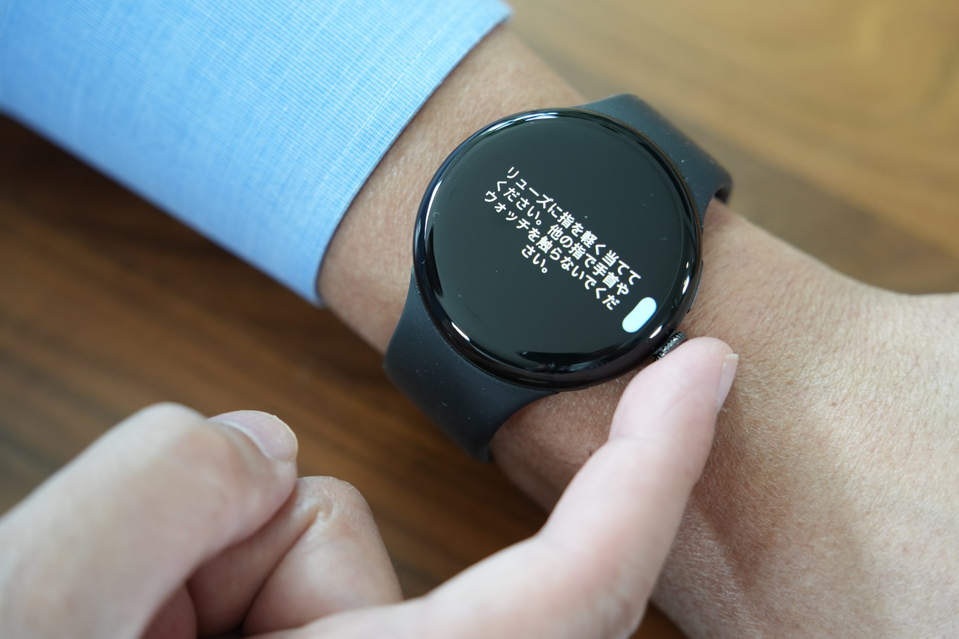 ウォッチを着けた腕を安定して置ける場所で、もう片方の手の人差し指をリューズに当てる