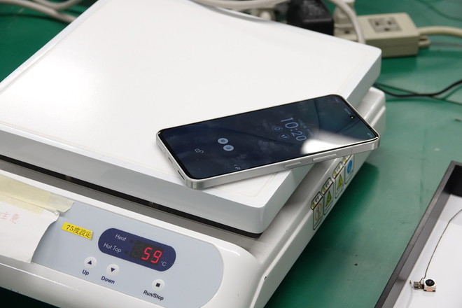 背面カバーは本体の金属製筐体に両面テープで接着されている。そのテープを剥がれやすくするため、「arrows Alpha」本体を丸ごと加熱していく。「arrows Alpha」はバッテリーを含めて高温下での保管や使用ができるよう設計されているので、この程度なら加熱しても問題はないという</br>※分解時に注意すべきポイントについて、十分な知識を備えたエンジニアによるものなので、絶対にマネはしないでください