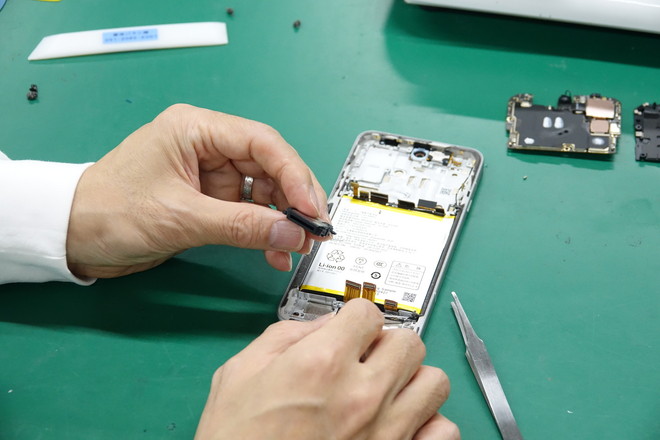 左手が持つ小さな黒いパーツはスピーカーモジュール。外部に音を出す必要があるので、スピーカーがセットされる筐体部分には特殊なフィルターで防水処置が施されている