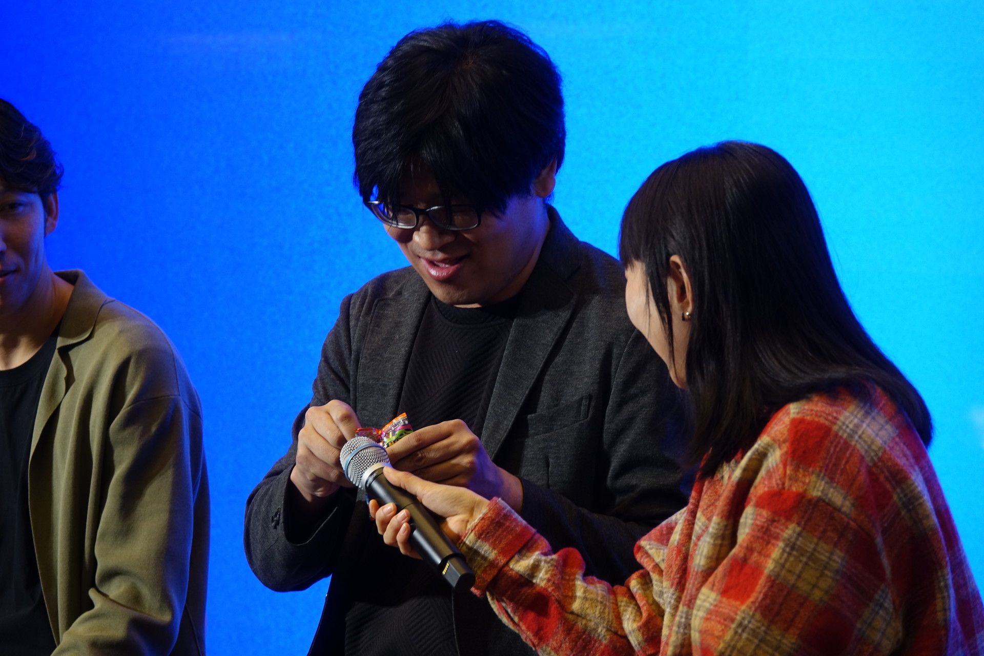 齊藤氏にうながされ、紙のパックを開封する辻川氏