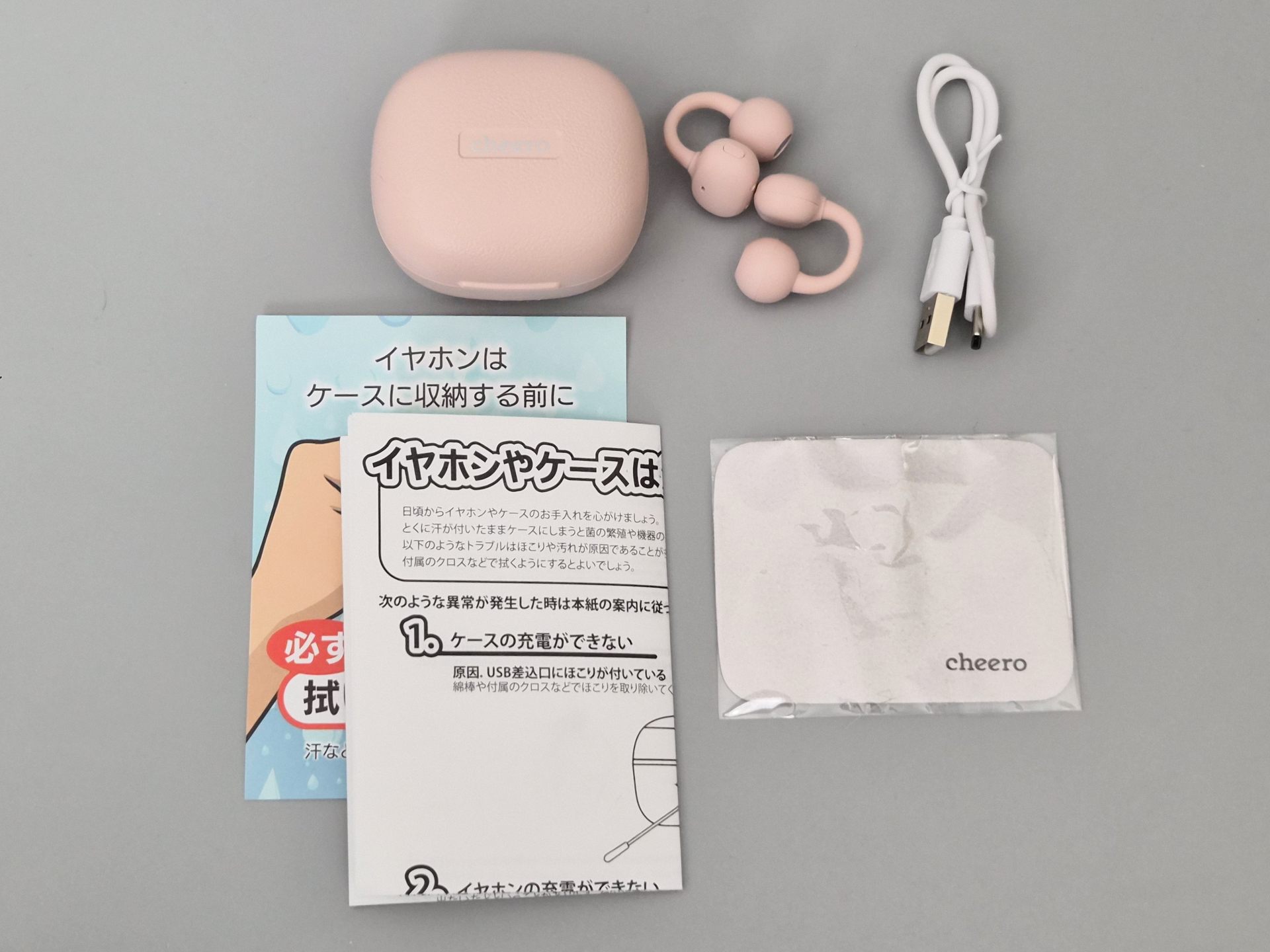 付属物全体。取扱説明書等の紙類と、本体、ケース、充電ケーブル、そしてクリーニングクロスがパッケージに含まれる