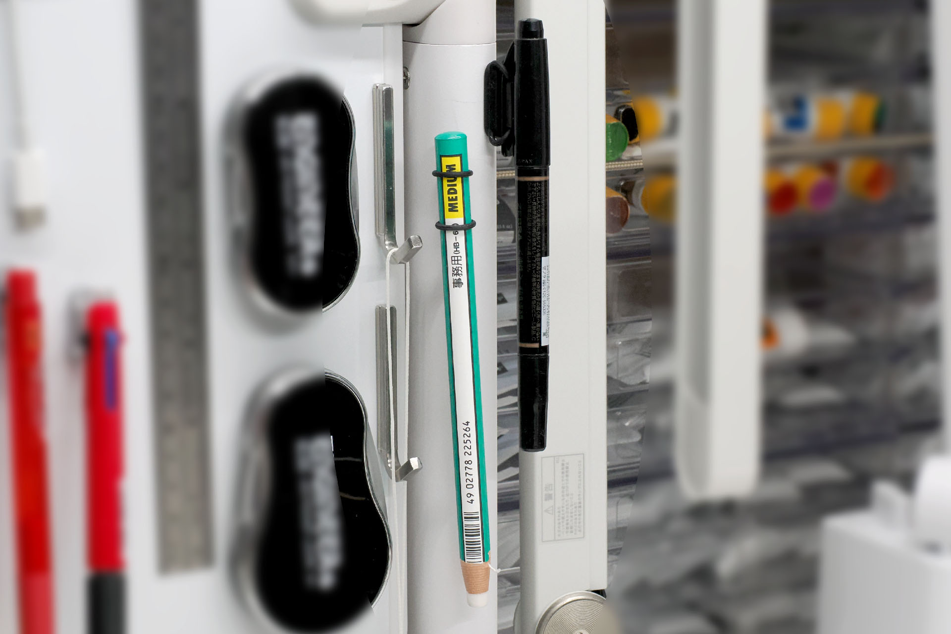 使用頻度が低いペン類も「空中収納」。サンコー「360度自由自在クランプ式ホワイトボード」の支柱部分はスチールなのでマグネットが吸着する。それを利用して油性マーカーとペン型消しゴムを「空中収納」している。