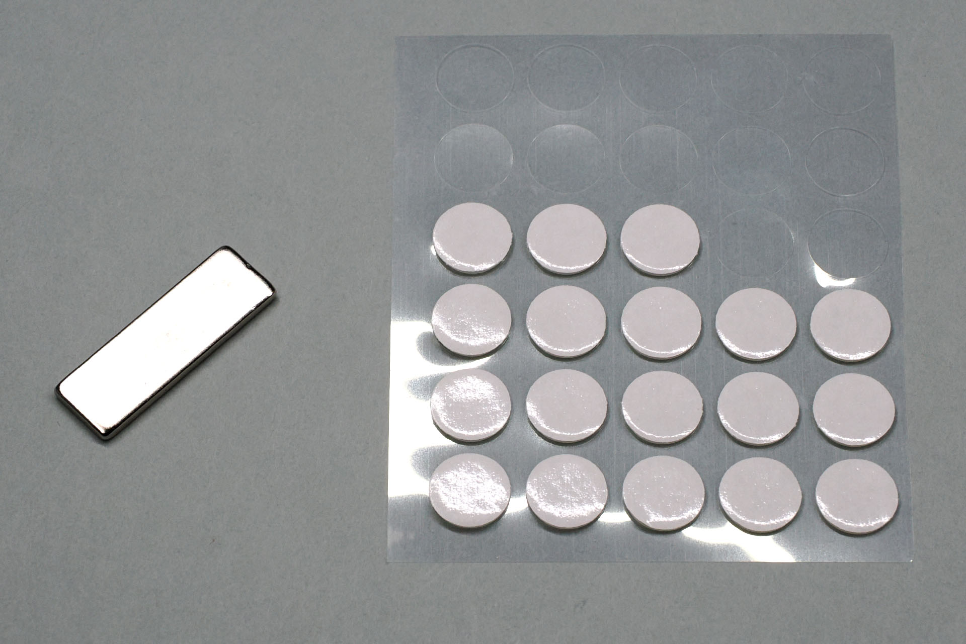 薄くて小さいネオジム磁石と、それを対象に貼るための「魔法のテープ」の類。「魔法のテープ」とは近年流行りのアクリル素材のジェル粘着剤で、強力な粘着力がありつつも、対象から粘着剤を除去しやすい。