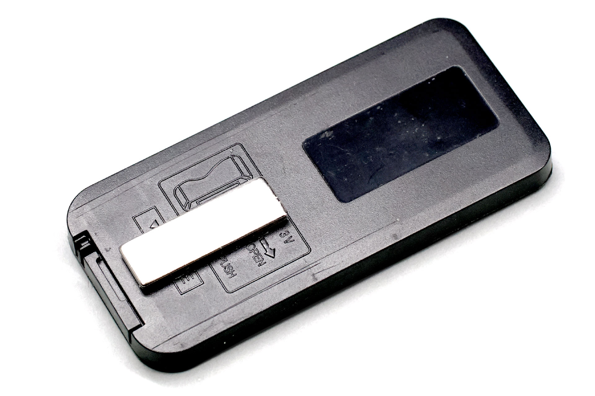 リモコンの裏に薄くて小さいネオジム磁石を貼った様子。アクリル素材のジェル粘着剤の粘着力は、小さめ薄めのネオジム磁石のスチールに対する吸着力を上回ったりするので、この貼り付け方でも「磁石が外れる」などの問題が起きにくい。