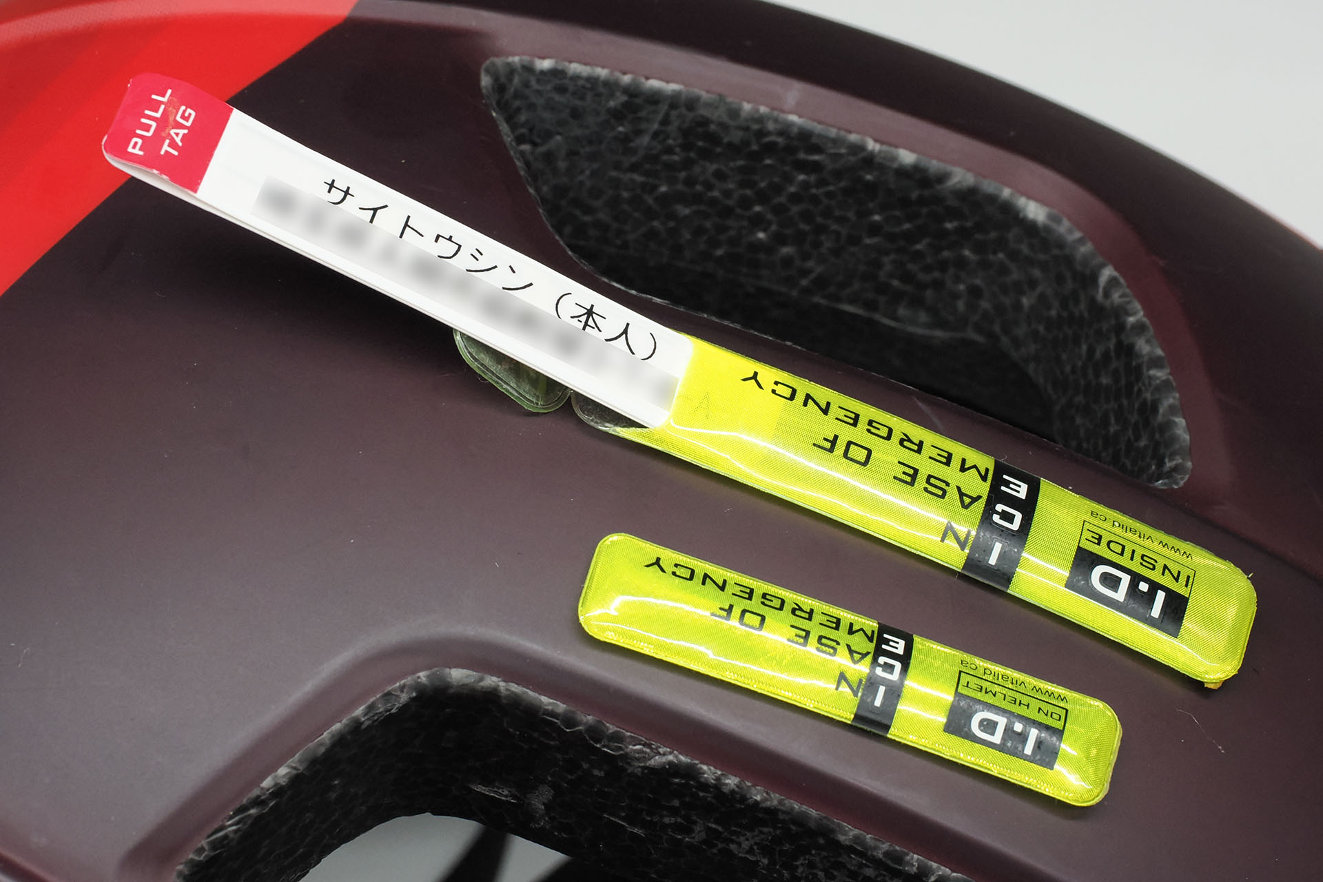 情報を書き込んだ細長いカードを折ってケースに入れ、そのケースをヘルメットに貼るタイプ。ただ、走行中にヘルメットに木の枝や雑草がかすったりすると剥がれやすい。またこのヘルメットは表面がマットな質感であるため、ケースの粘着が十分強くないので、この緊急連絡先グッズは使うのをやめようと考えている。ちなみにこのグッズは以前は1枚単位で購入可能だったが、現在は20枚とか50枚の単位でないと買えなくなっている。