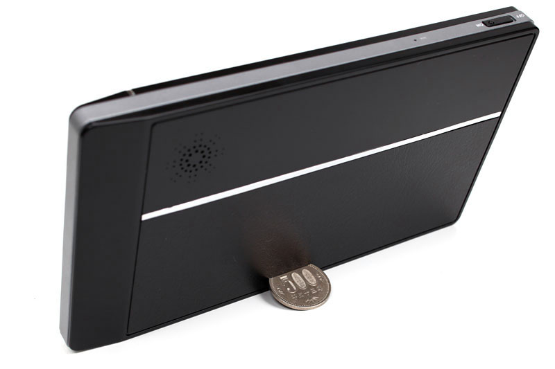 本体背面下部のスリットに500円玉を挿すと、このように自立させることができる。裏面左上がスピーカー。右上にはマイクと電源スイッチがある