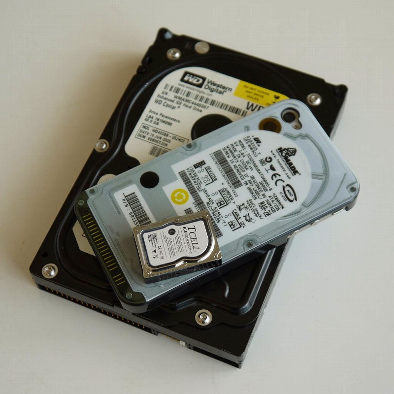 一番下の黒い3.5インチのハードディスクが異常に大きく見える。2段目はハードディスク・スタイルのカバーを取り付けた筆者のiPhone4。一番上に載ってる小さなHDDがTCELL