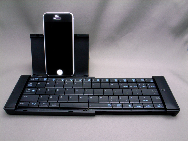 ユニークな横スライド方式のBluetoothキーボード「TK-FBP049E」。iPhone 5をスタンドに載せている