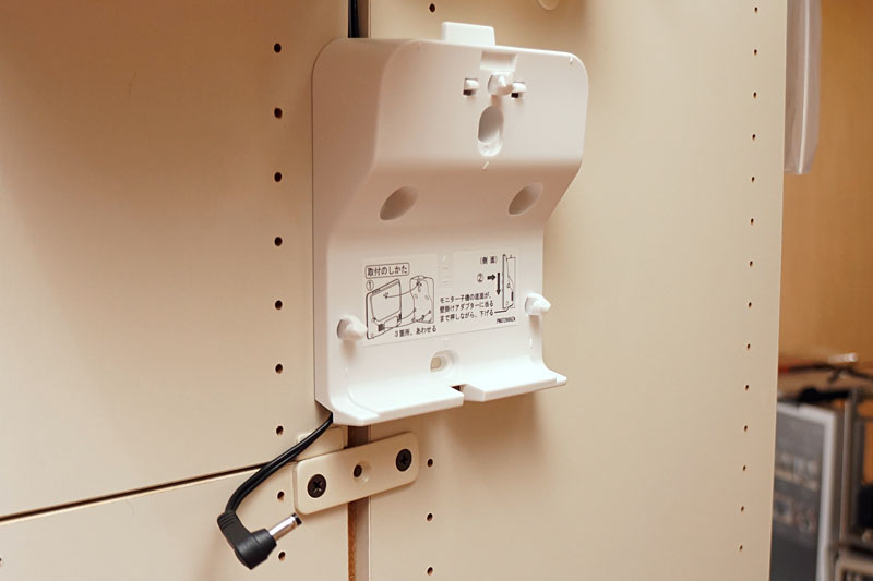 カラー子機を壁掛けにするための「壁掛けアダプター VS-U200」。壁（この場合は本棚）にネジ止めする。アダプターに対してカラー子機の脱着を自由に行えて便利っす。