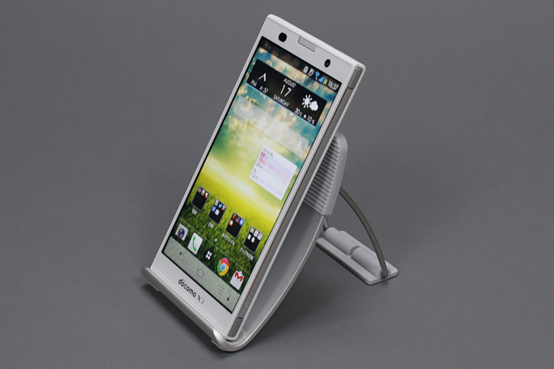 「Arrows NX F-06E」をセットした様子。スマホには大きめという感じもするが、実用的。横置きにすると本体とスタンド金属部が接触するが、あまり気にならないので付属のラバーパッドは貼っていない