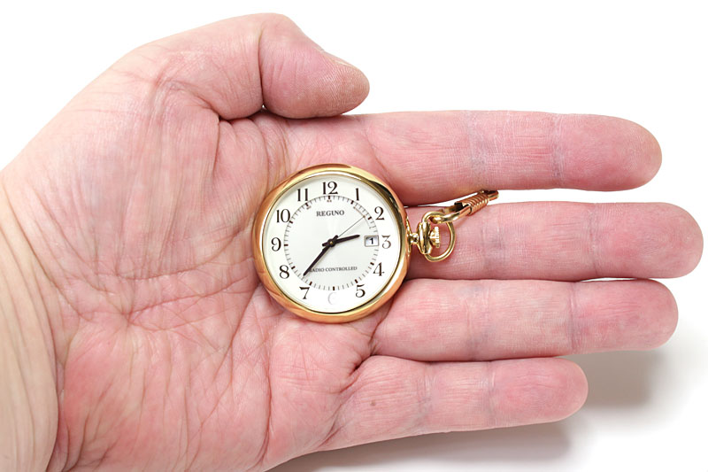 右にリュウズおよびチェーンがあるので、指の間にチェーンを通してポケットなどから出せば、そのまま違和感なく文字盤を見られます。リュウズが上にある懐中時計の場合、人差し指と親指の間に鎖をかければ、違和感なく文字盤を見られます。