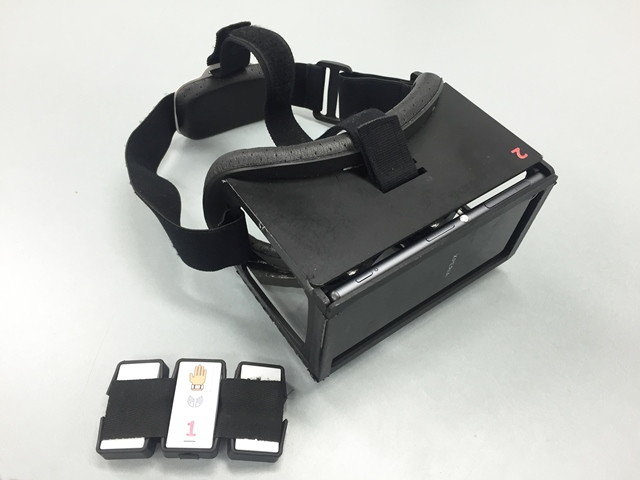 スマートフォンが装着されたヘッドマウントディスプレイと、センサー内蔵のアームバンドを装着