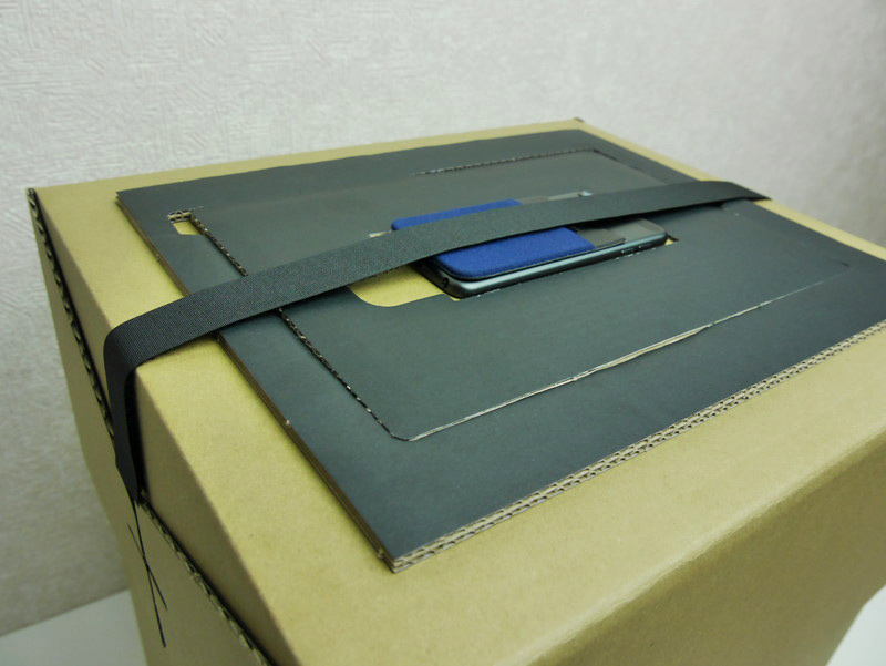 スペーサーを段ボール上面にセットし、端末も設置。落下防止用の帯状のマジックテープも取り付けて準備完了