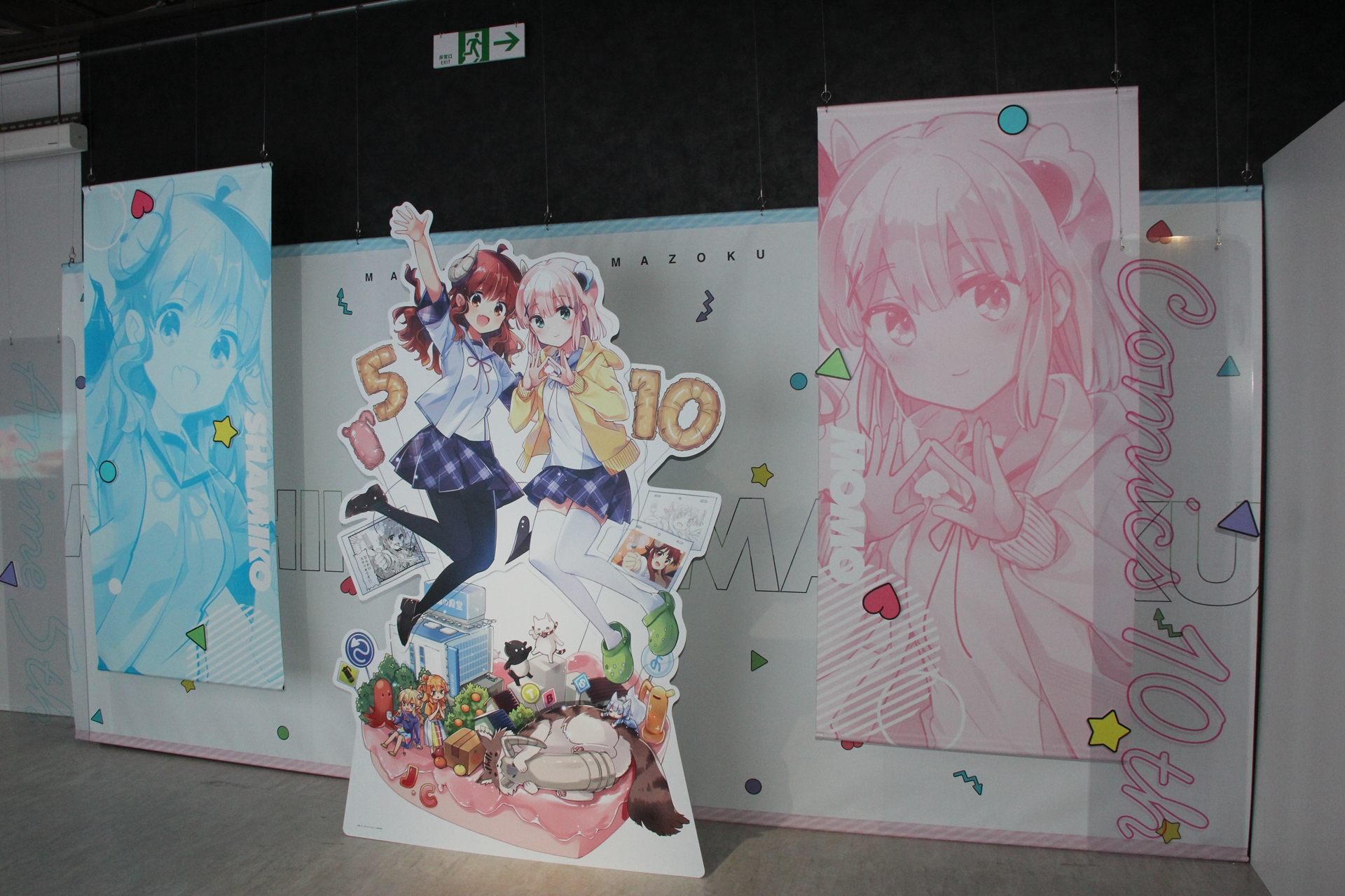 反対側には、本展示会のために描き下ろされたパネルと共に、コミック10周年とアニメ5周年を祝う巨大なポップも展示されていた