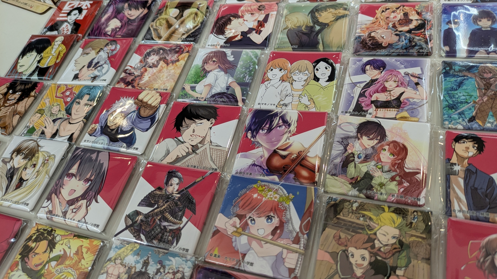 物販コーナーのお品書きと展示。缶バッジやアクスタといったアイテムのほか、数量限定で複製原画の販売（デジタルサイン入りの「一勝千金」のみ受注販売）なども行なわれる。複製原画は展示も行なわれていたが、思わず「これが買えてしまうのか……」と思ってしまうほどの出来栄えだった