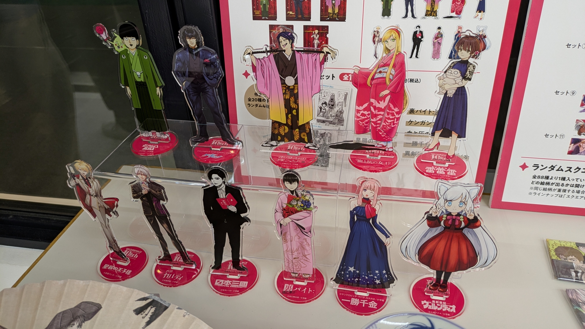 物販コーナーのお品書きと展示。缶バッジやアクスタといったアイテムのほか、数量限定で複製原画の販売（デジタルサイン入りの「一勝千金」のみ受注販売）なども行なわれる。複製原画は展示も行なわれていたが、思わず「これが買えてしまうのか……」と思ってしまうほどの出来栄えだった