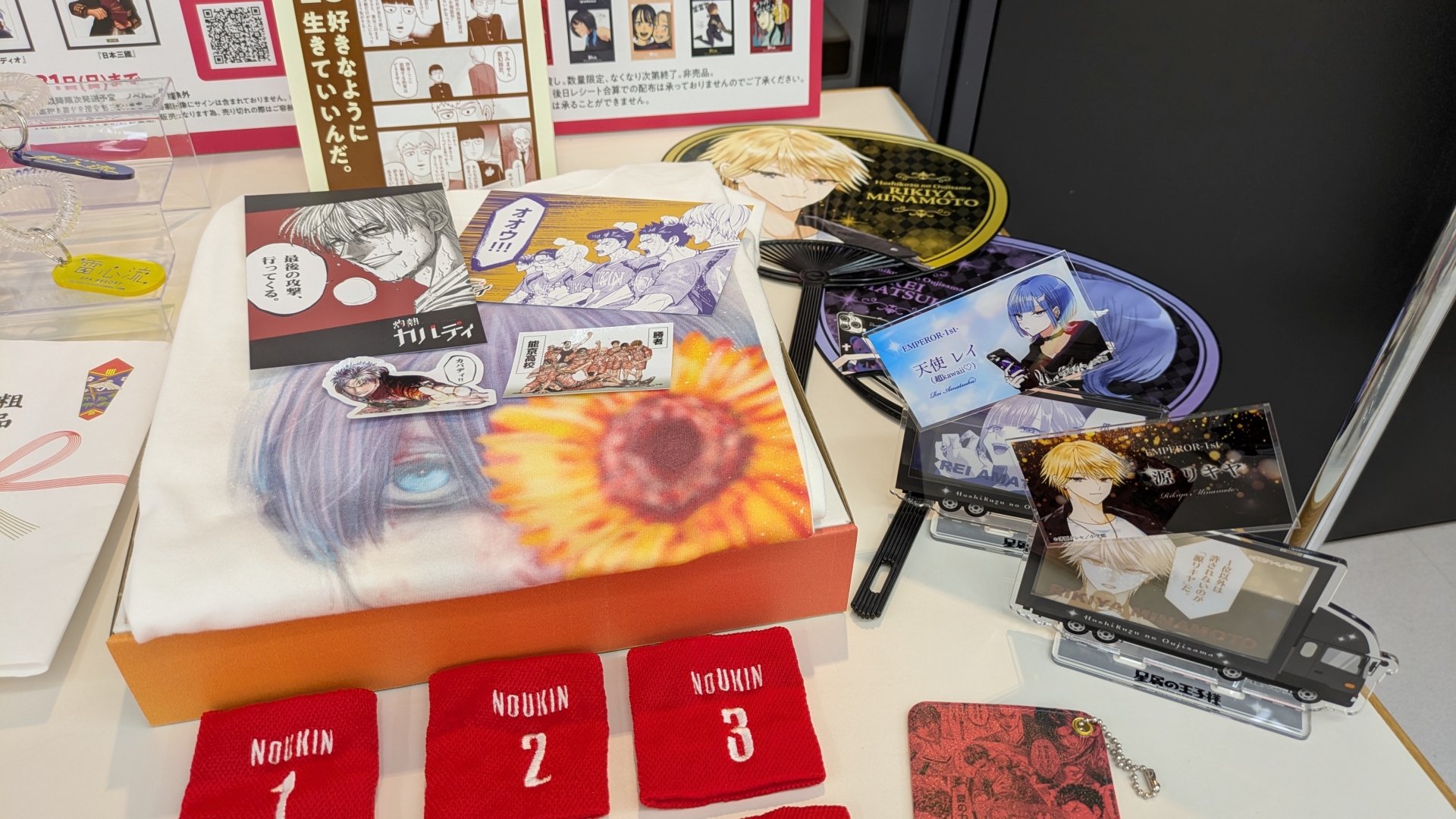 物販コーナーのお品書きと展示。缶バッジやアクスタといったアイテムのほか、数量限定で複製原画の販売（デジタルサイン入りの「一勝千金」のみ受注販売）なども行なわれる。複製原画は展示も行なわれていたが、思わず「これが買えてしまうのか……」と思ってしまうほどの出来栄えだった