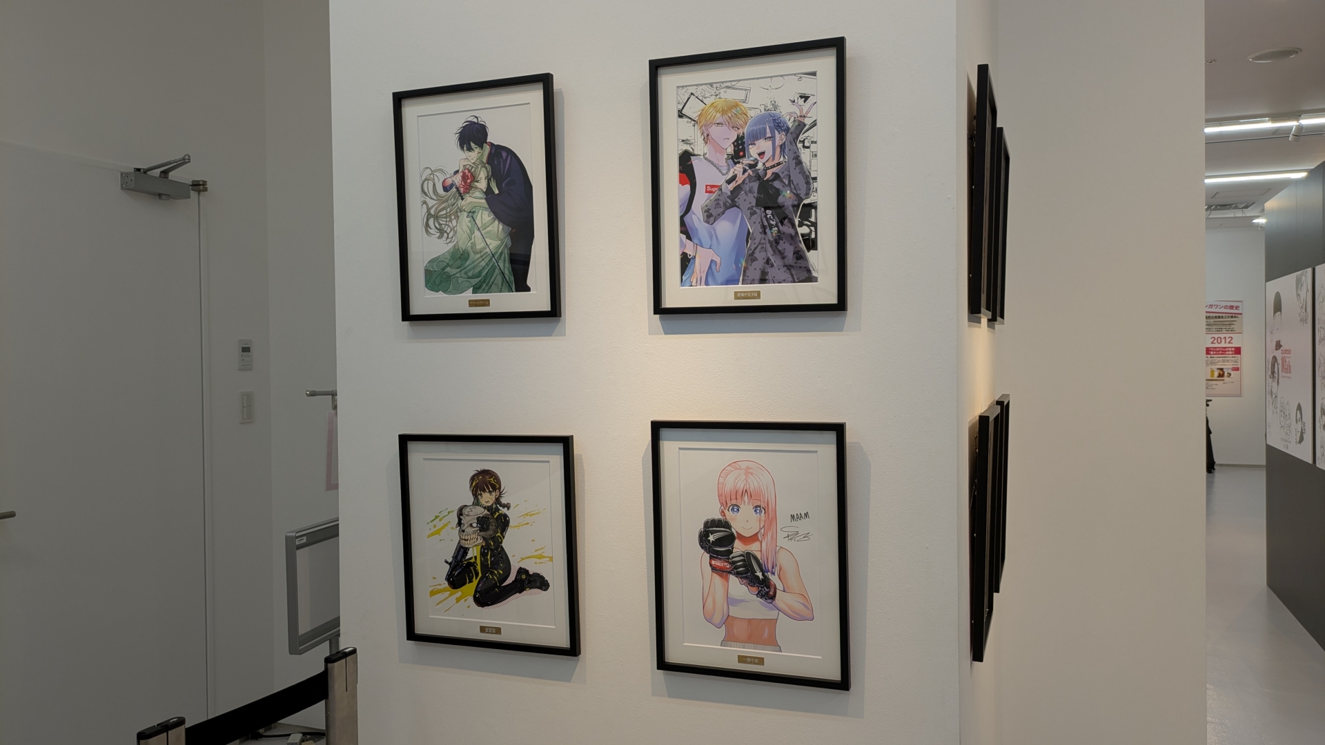 物販コーナーのお品書きと展示。缶バッジやアクスタといったアイテムのほか、数量限定で複製原画の販売（デジタルサイン入りの「一勝千金」のみ受注販売）なども行なわれる。複製原画は展示も行なわれていたが、思わず「これが買えてしまうのか……」と思ってしまうほどの出来栄えだった