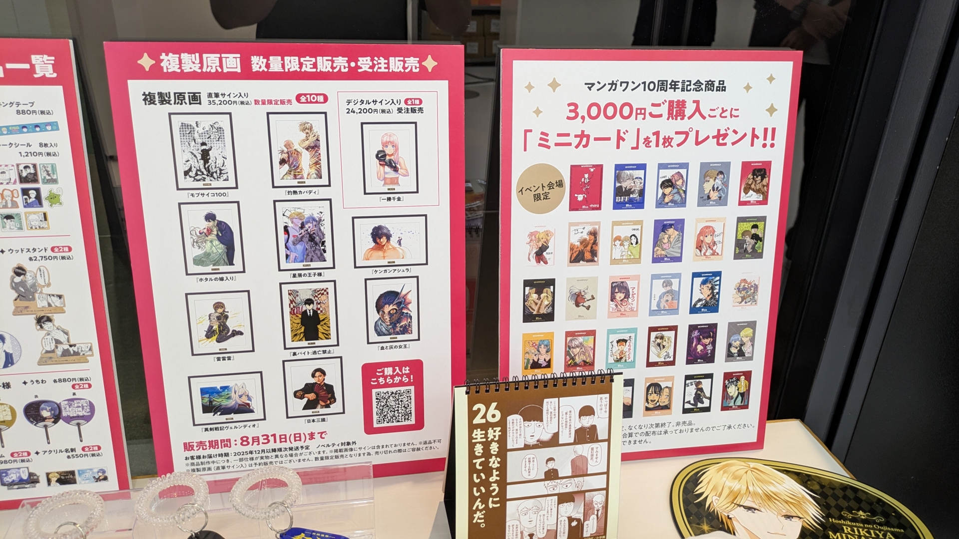 物販コーナーのお品書きと展示。缶バッジやアクスタといったアイテムのほか、数量限定で複製原画の販売（デジタルサイン入りの「一勝千金」のみ受注販売）なども行なわれる。複製原画は展示も行なわれていたが、思わず「これが買えてしまうのか……」と思ってしまうほどの出来栄えだった