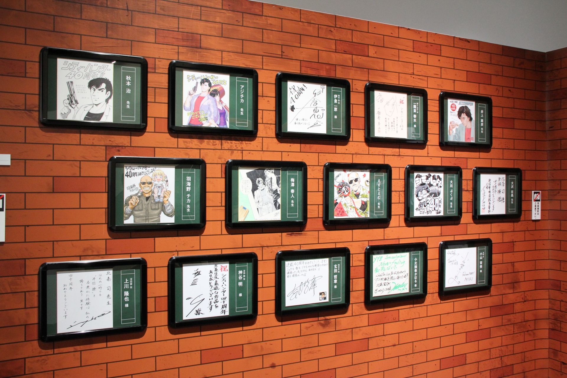 漫画家やアーティストからの、御祝サイン色紙も展示中。その隣には、クラウドファンディングに協力してくれた人への返礼伝言板も置かれている