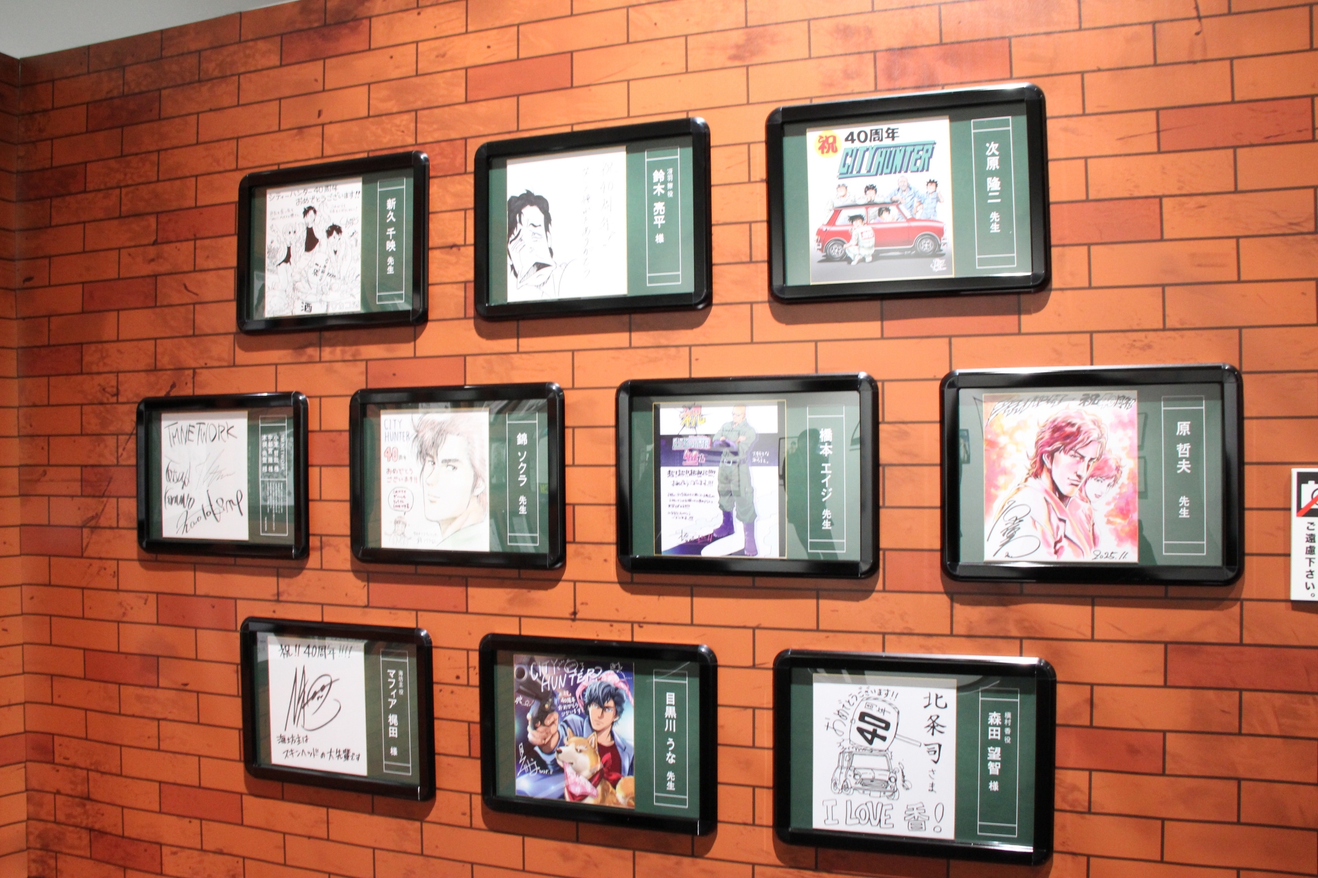 漫画家やアーティストからの、御祝サイン色紙も展示中。その隣には、クラウドファンディングに協力してくれた人への返礼伝言板も置かれている