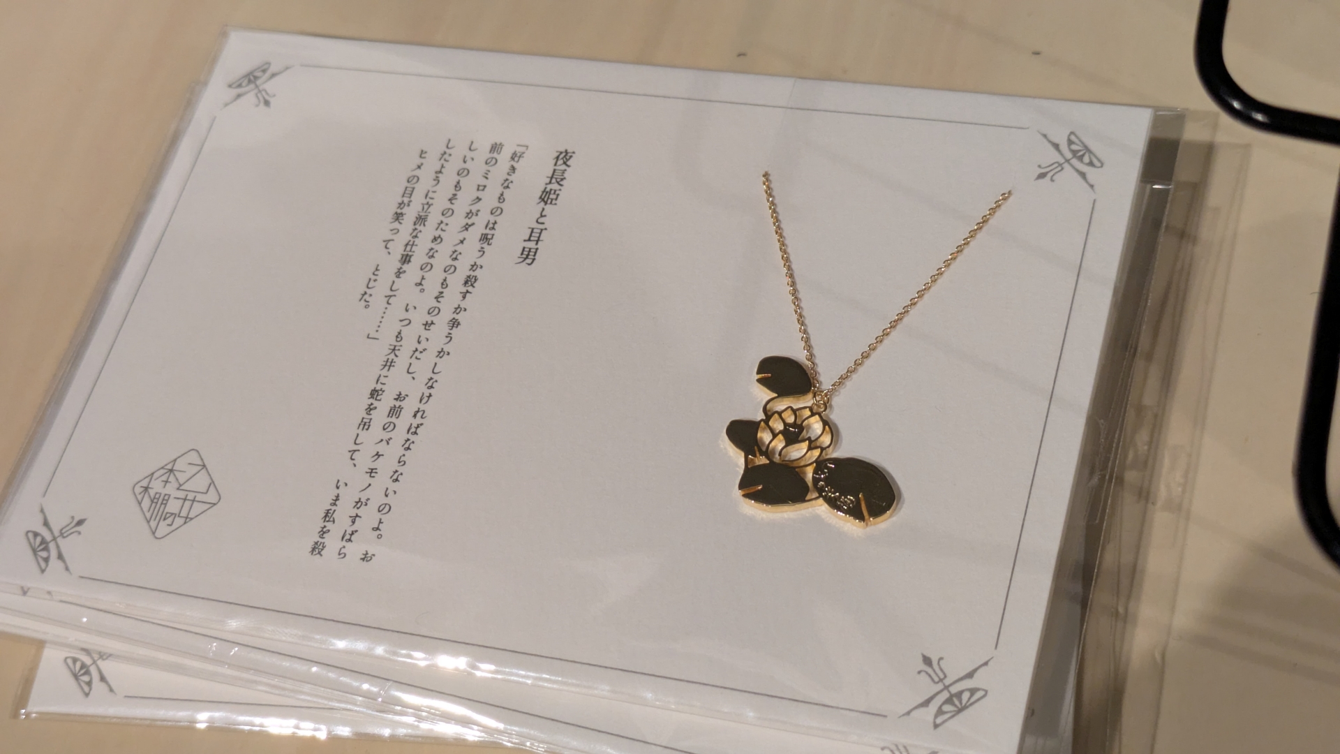 「夜長姫と耳男」の印象的な一節が台紙に記された睡蓮モチーフのネックレス