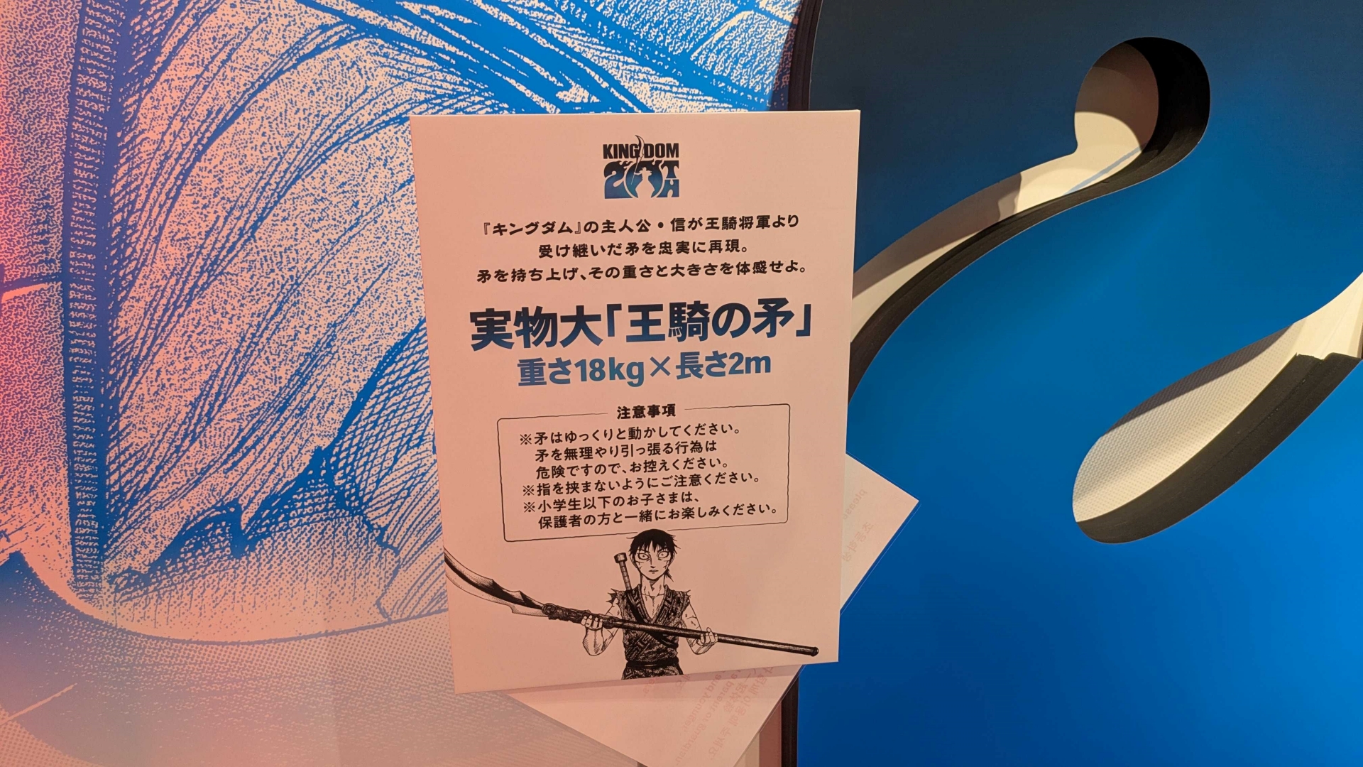 約2m、重量18kgの実物大「王騎の矛」を持ち上げて写真を撮れるフォトスポット。実際握ってみるとずっしりと重く、これを軽々と扱う王騎将軍の膂力がよくわかる