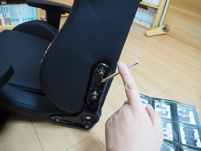 まず、背もたれ部の両脇から仮留めされている4本のネジを取り外し、背もたれ部と座部を合体させてから、4本のネジで取り付ける。4本のネジは、いったん手である程度回してすべて仮留めしてから、レンチで本締めすると良い。なお今回は写真を撮影するため素手で作業したが、皆さんが組み立てる際には怪我防止のために付属の軍手を使ってほしい