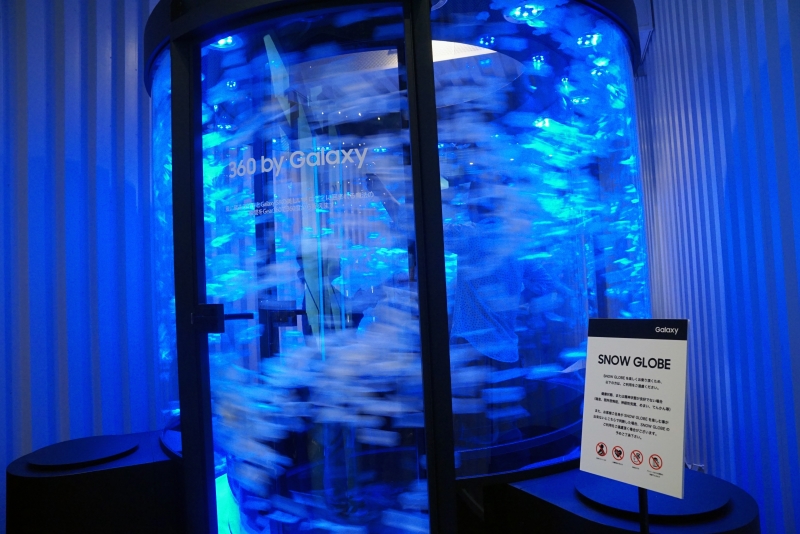 ガラスで囲まれた円形空間に入り、内部で吹き荒れる花びらを360度カメラの「Gear 360」で撮影して楽しむアトラクション「SNOW GLOBE」。Gear 360は4K解像度に対応したカメラで、手軽に持ち運べる携帯性やライブビュー撮影機能、IP5X/IPX3の防塵・防滴仕様などを特徴としている