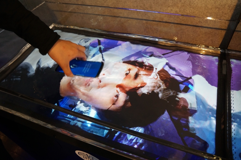 Galaxy S8/S8+の防水仕様を体験するための「LIQUID CANVAS」では、Galaxy S8/S8+で自撮りをし、そのまま水槽に付けて前後左右へと動かすことで、水槽の下にあるディスプレイにエフェクトとともに自分の顔が浮かび上がってくる。ペイントブラシに見立てられたスマホで、肖像画のスケッチ体験ができるというアトラクション